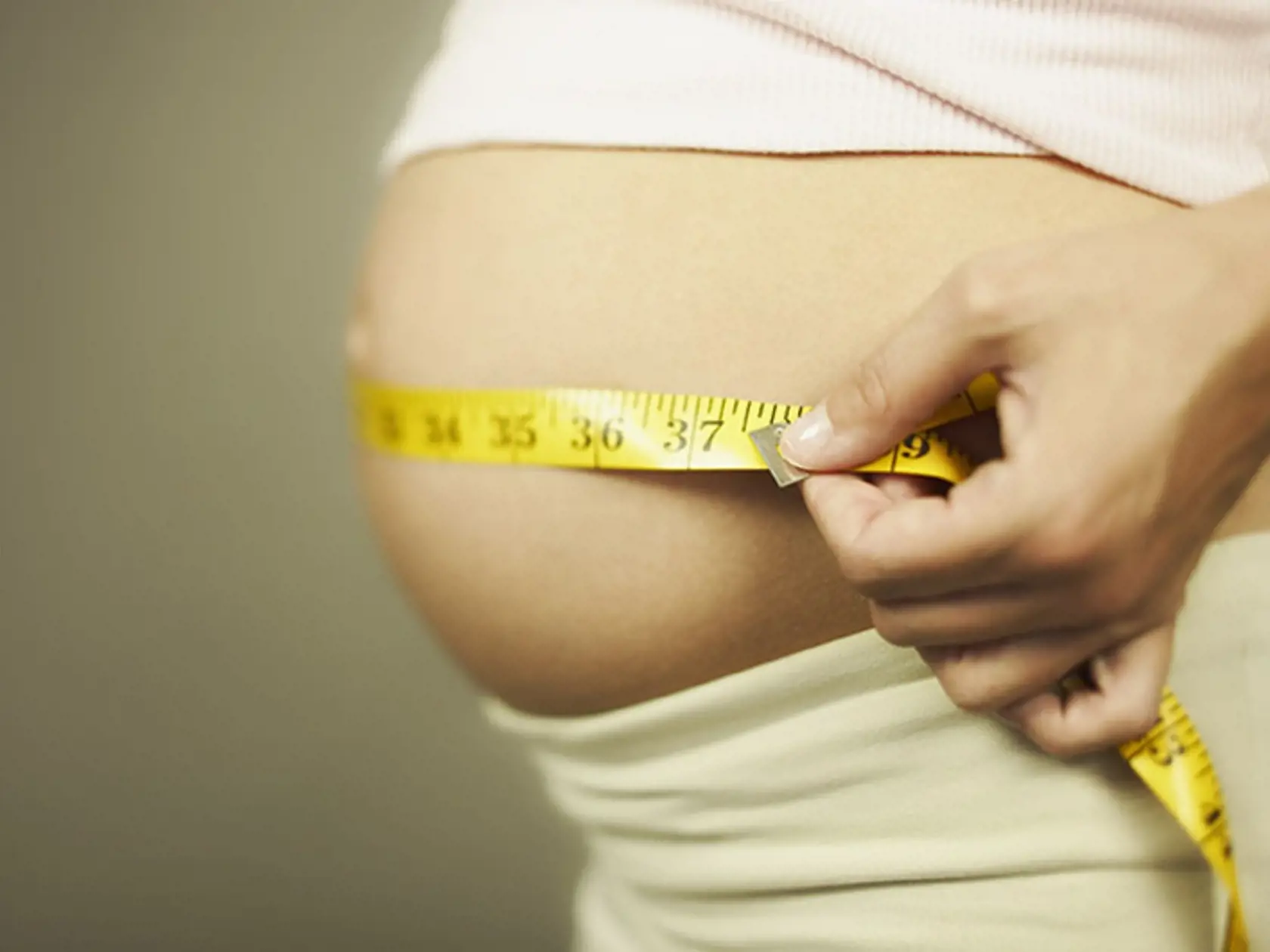 Cropped pregnant woman measuring waist