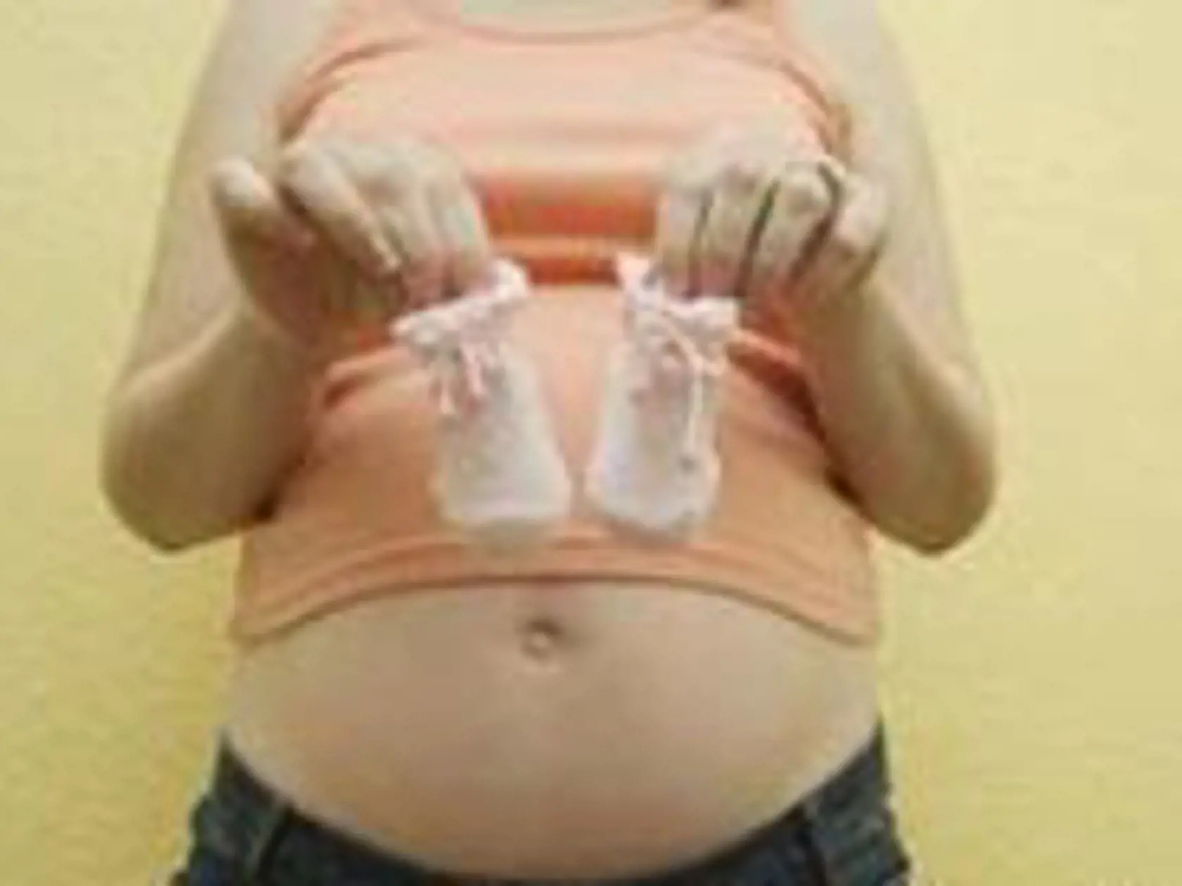 Pregnant Woman Holding Baby Booties --- Image by © Royalty-Free/Corbis
