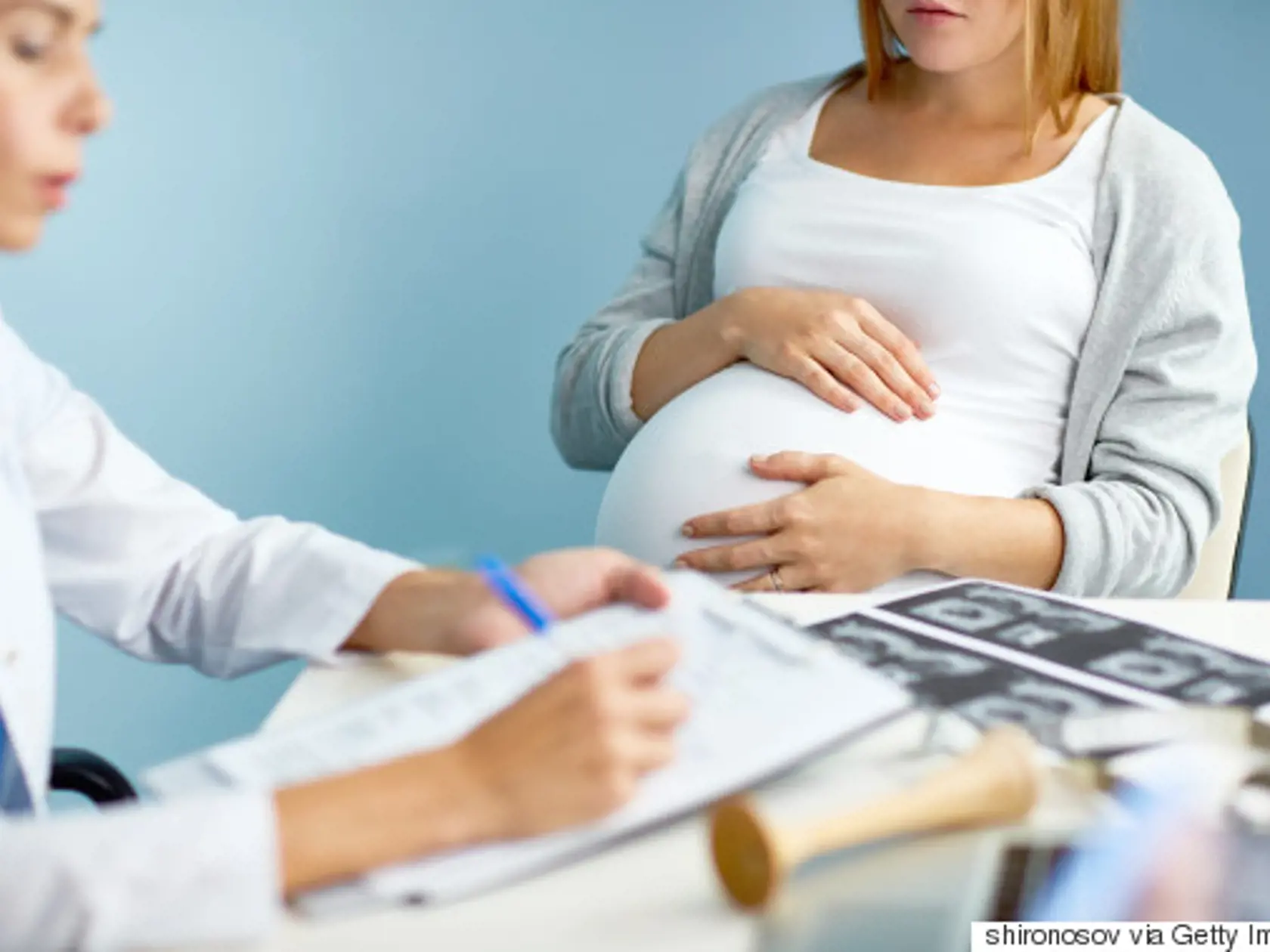 Hands of pregnant woman on her abdomen during visit to obstetrician