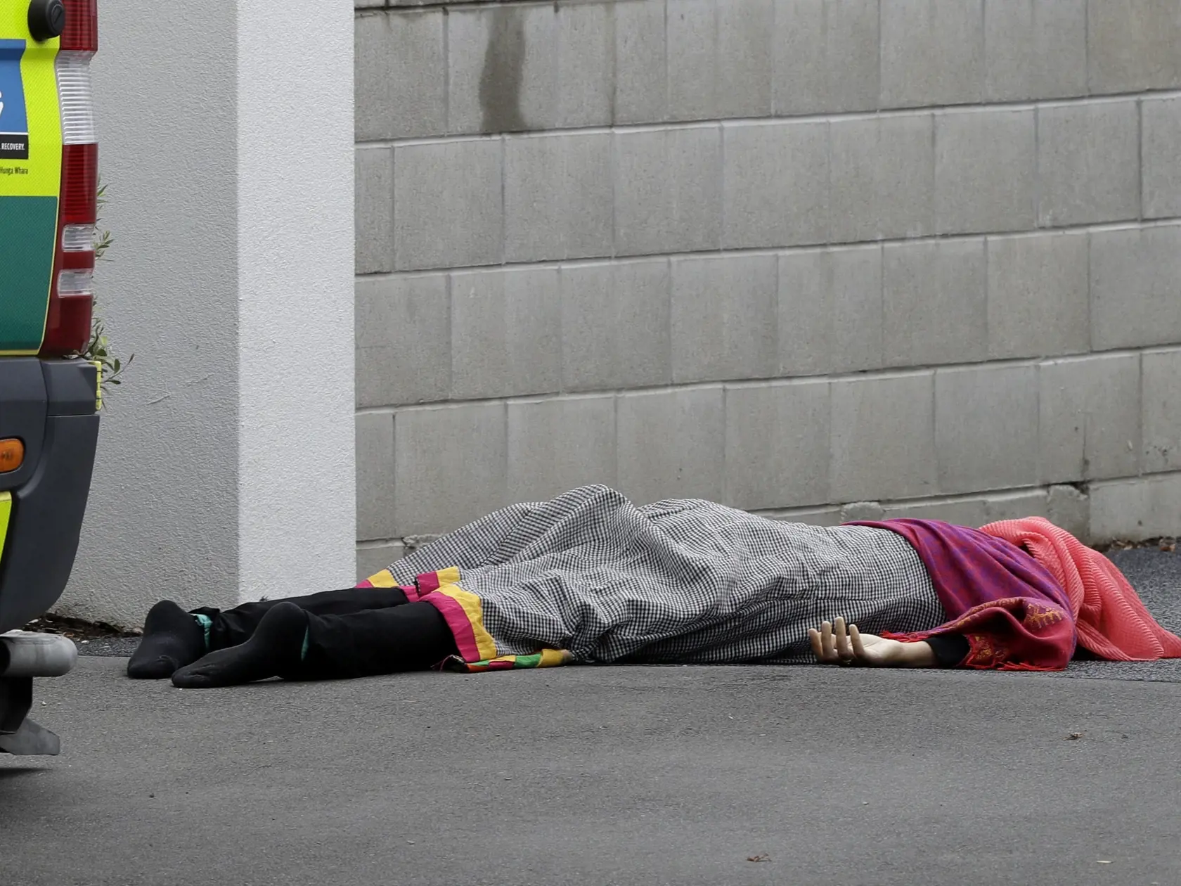 A body lies on the footpath outside a mosque in central Christchurch, New Zealand, Friday, March 15, 2019. A witness says many people have been killed in a mass shooting at a mosque in the New Zealand city of Christchurch. (AP Photo/Mark Baker)
