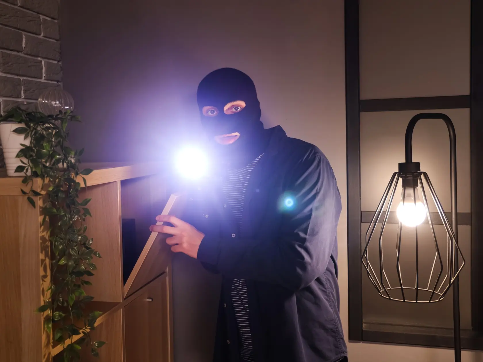 Male,Thief,With,Flashlight,Looking,For,Money,In,Room,At