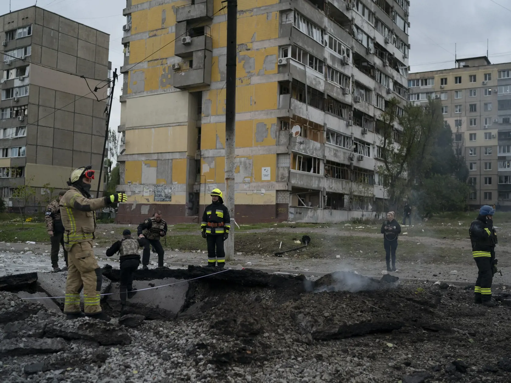 Na snímke hasiči a policajti zasahujú na mieste, kde výbuch vytvoril na ulici kráter po ruskom útoku v ukrajinskom meste Dnipro 10. októbra 2022.