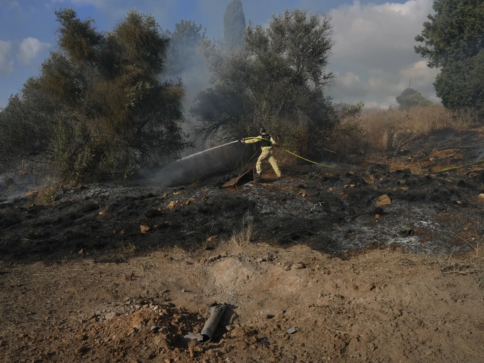 Izraelský hasič sa pokúša uhasiť požiar spôsobený raketou vypálenej z Libanonu pri meste Naharija, na severe Izraela neďaleko hranice Izraela s Libanonom 30. septembra 2024.