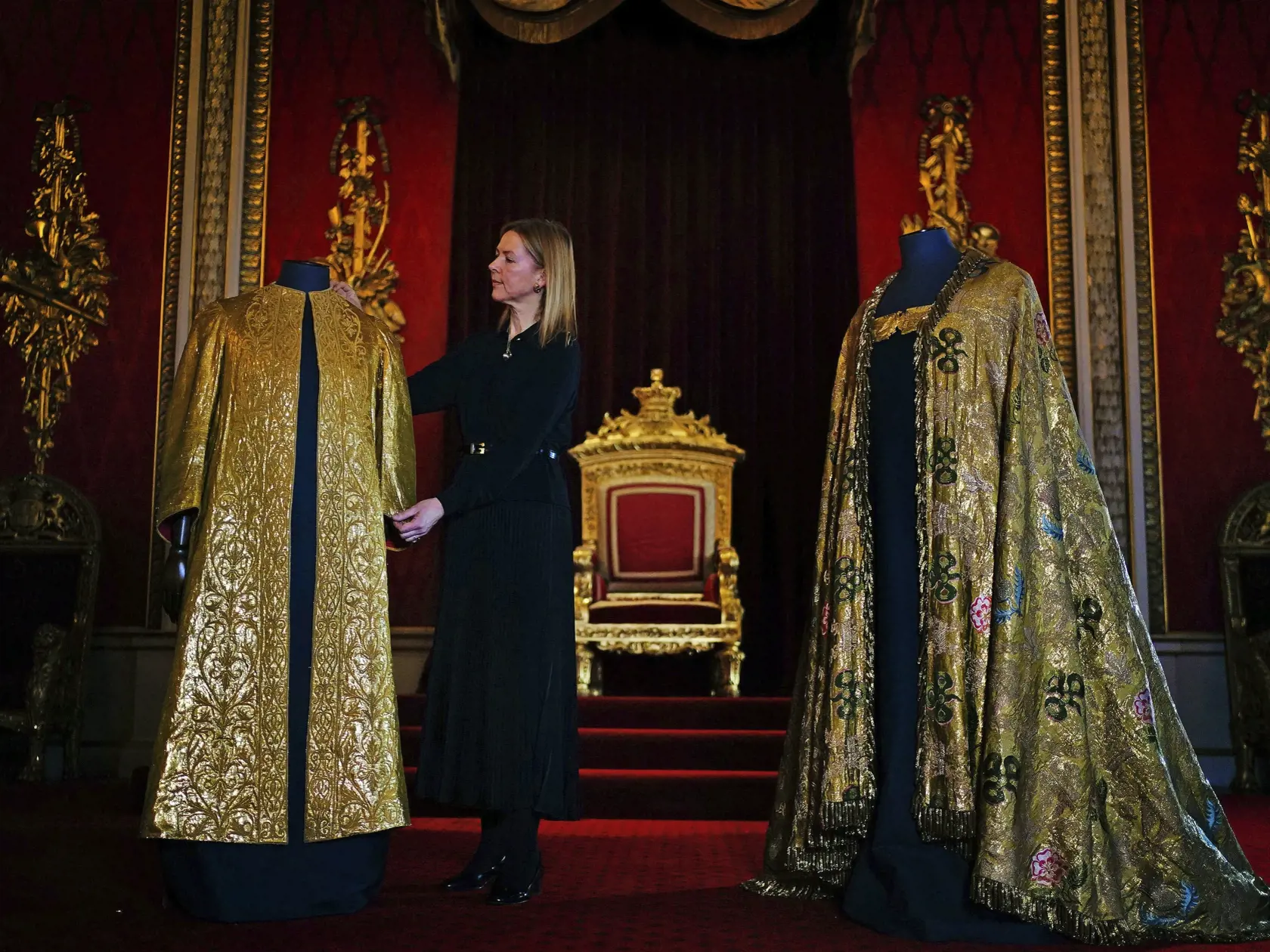 Na snímke vyšívaná zlatá tunika (vľavo) z roku 1911, ktorú bude mať na sebe oblečenú britský kráľ Charles III. počas pomazania a následne  bude mať potom na tunike ešte oblečený kráľovský plašť (vpravo) z roku 1821, v Buckinghamskom paláci 26. apríla 2023 v Londýne.