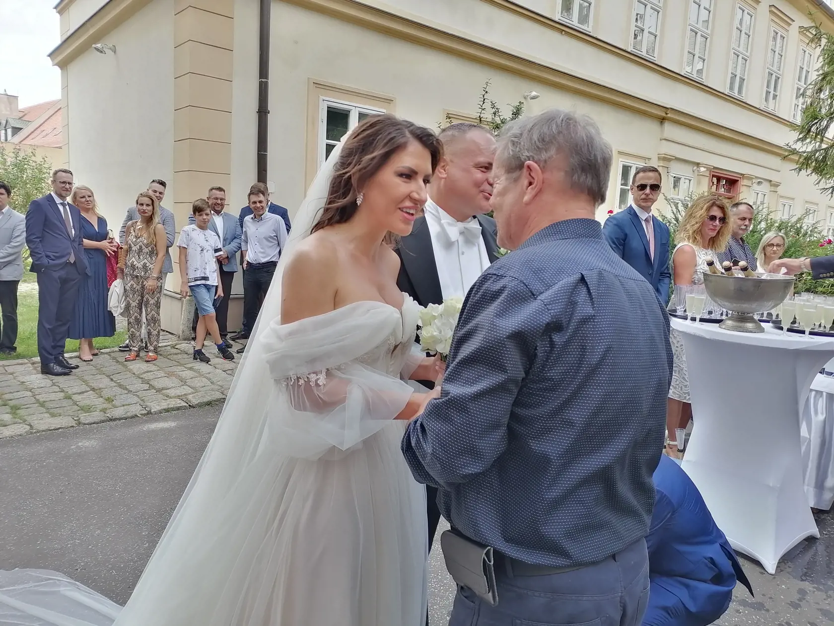 Pred kostolom bolo obrovské množstvo svadobčanov, ktorí sa snažia dostať k mladomanželom a zablahoželať im.