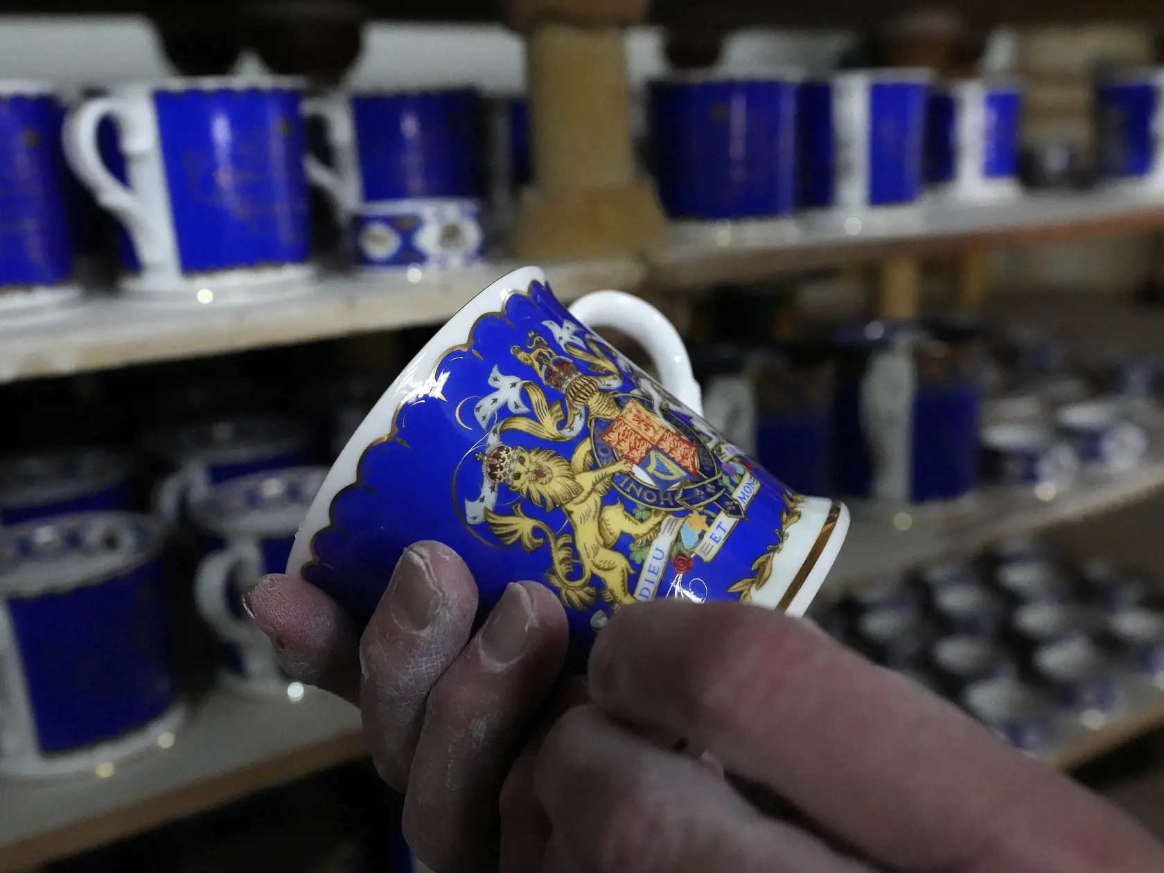 Pracovník kontroluje kvalitu porcelánu vo výrobni 13. apríla 2023 v v Stoke-on-Trent. V piatok 14. apríla sa začal  predávať sortiment oficiálneho porcelánu na blížiacu sa korunováciu britského kráľa Charlesa III., ktorá sa bude konať 6. mája vo Westminsterskom opátstve.