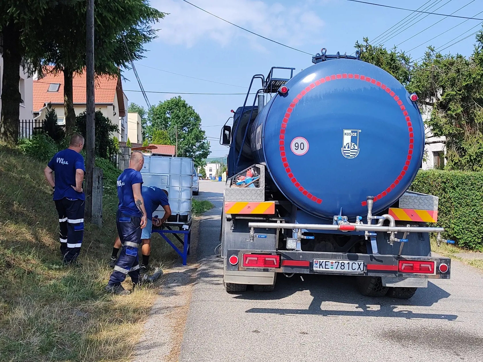 Na snímke pracovníci Východoslovenskej vodárenskej spoločnosti (VVS) umiestňujú na uliciach v obci nádrže s pitnou vodou v Ruskove 2. júla 2022. Nedostatok pitnej vody následkom sucha a horúčav postihuje už aj okolie Košíc. V obci Ruskov zaznamenali výpadky vody v domácnostiach od piatka (1. 7.) rána, situáciu riešia zásobovaním z cisterny. FOTO TASR - Marián Holubčík