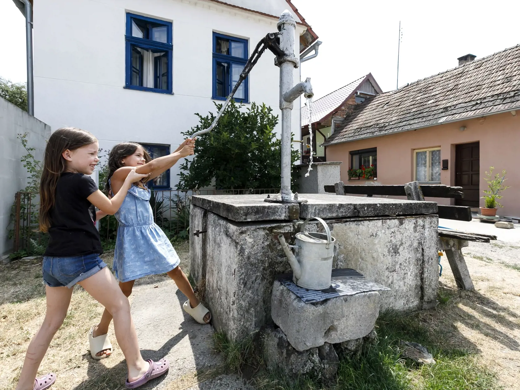 Extrémne sucho, ako aj vysoká spotreba vody počas mimoriadne teplých dní spôsobili, že viacerým obciam na Záhorí hrozí nedostatok vody vo verejných vodovodoch. Nedostatok vody sa týka viacerých obcí v záhorskom aj senickom skupinovom vodovode. Ide predovšetkým o obce Prievaly, Osuské, Jablonica, Cérová, Borský Mikuláš, Rohožník, Studienka a Lakšárska Nová Ves. Na snímke deti čerpajú vodu z obecnej studne v obci Osuské, okres Senica v utorok 26. júla 2022. FOTO TASR - Dano Veselský