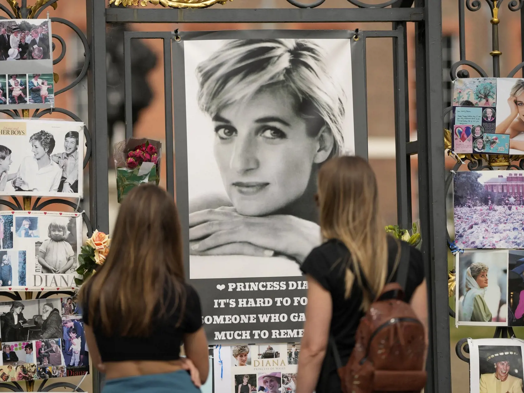 Na snímke ženy sa pozerajú na portréty princeznej Diany, ktoré visia na bránach Kensingtonského paláca 30. augusta 2022 v Londýne. Princezná Diana zahynula spoločne so svojím posledným partnerom Dodim al Fayedom 31. augusta 1997 po tom, ako ich auto havarovalo v parížskom tuneli. Vyšetrovanie z roku 2008 odhalilo, že príčinou smrti páru bola hrubá nedbanlivosť ich podnapitého šoféra Henriho Paula a tiež konanie paparazzov, ktorí ich počas celej jazdy prenasledovali.