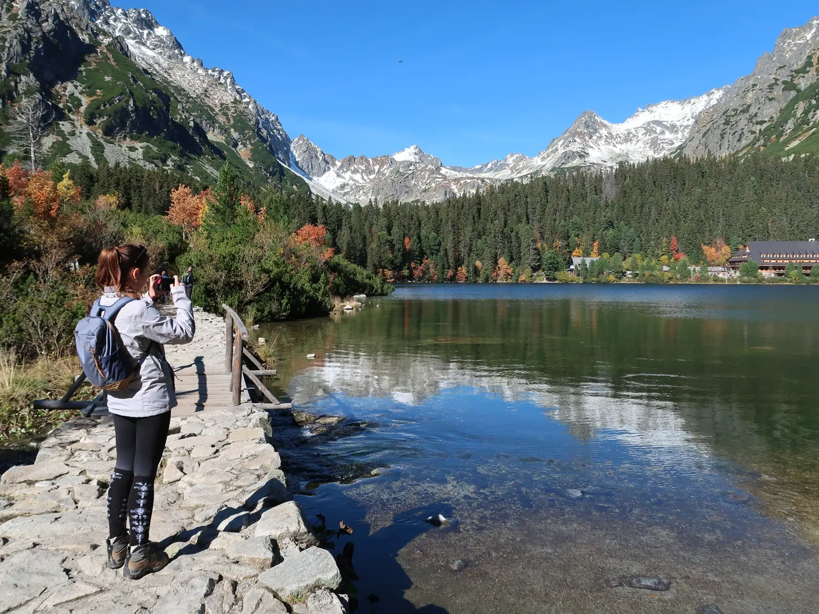 Babie leto v Tatrách si užívalo cez víkend množstvo turistov. Na snímke turistka  fotografuje jesenné Popradské pleso obklopené zasneženými vrcholmi Tatier v sobotu 8. októbra 2022. FOTO TASR - Adriána Hudecová
