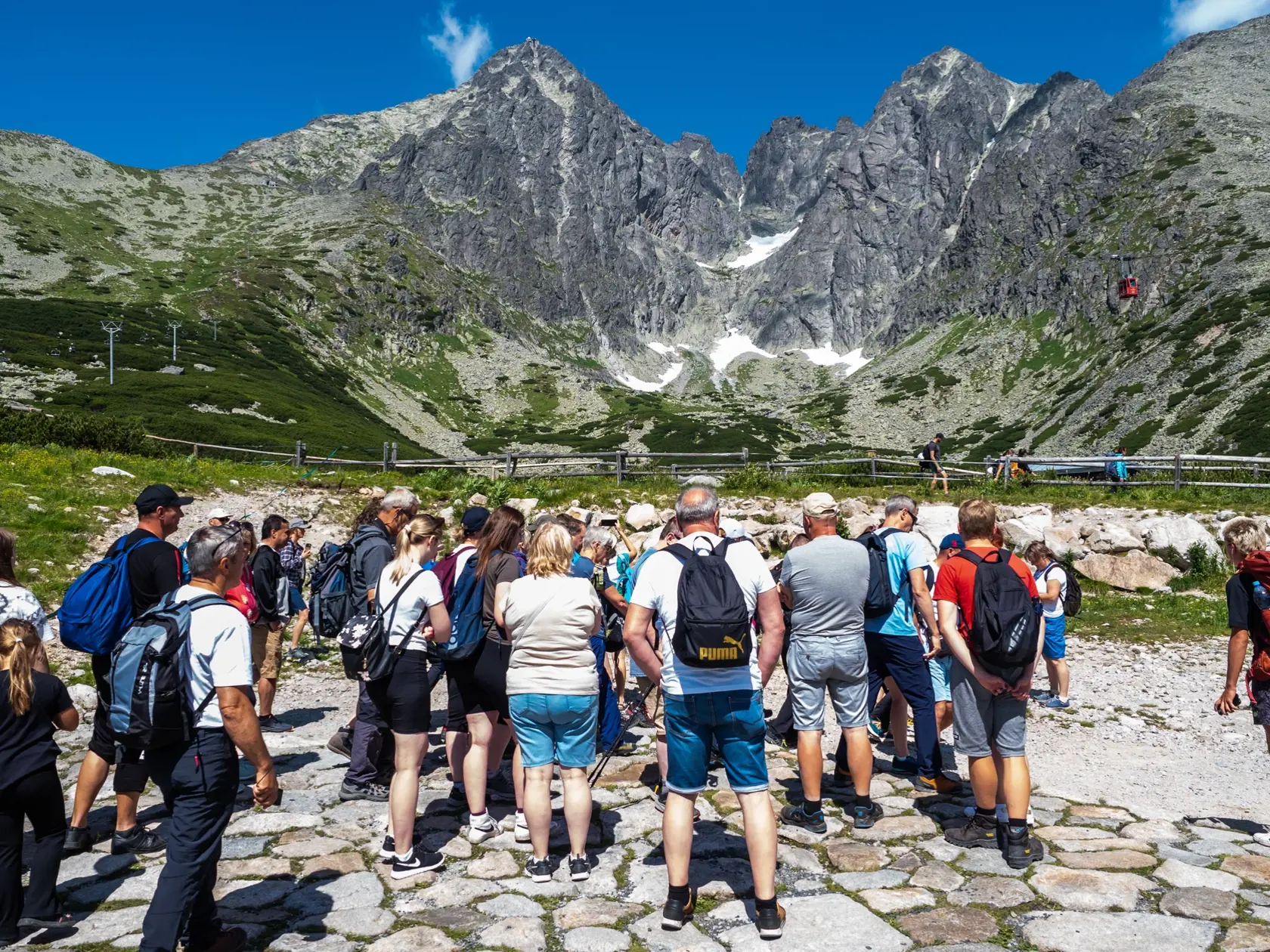 Na snímke turisti na Skalnatom plese vo Vysokých Tatrách, vpravo visutá lanovka smeruje na Lomnický štít  15. júla 2023. FOTO TASR - Veronika Mihaliková 