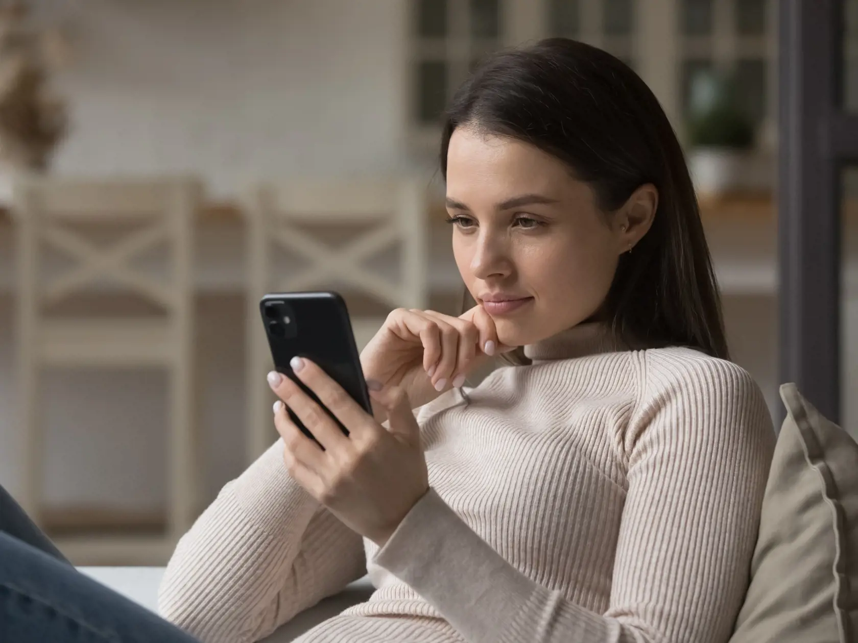 Focused,Millennial,Woman,Using,Mobile,Phone,At,Home,,Reading,Online