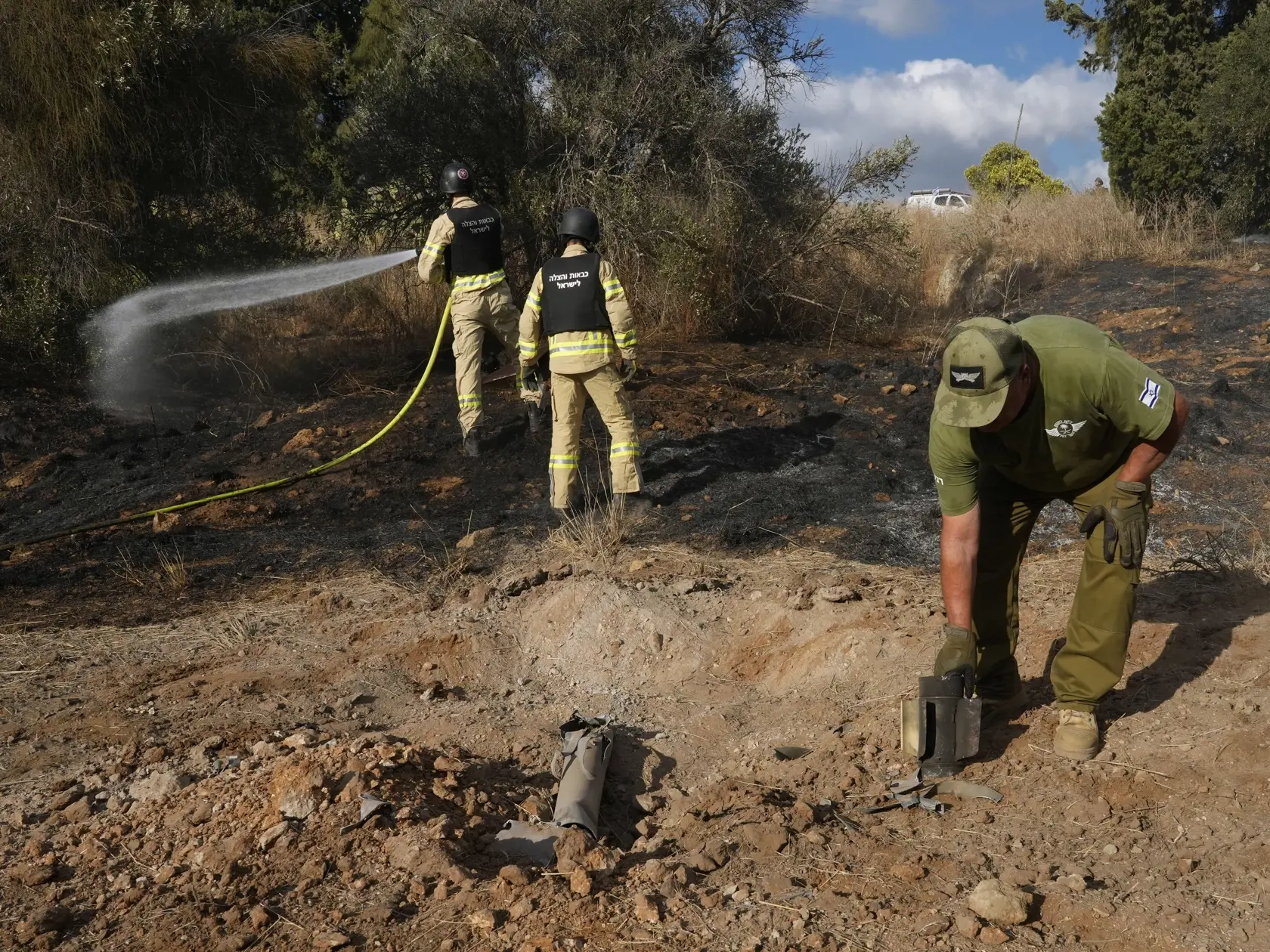 Izraelskí hasiči a pyrotechnici sa pokúšajú uhasiť požiar spôsobený raketou vypálenej z Libanonu pri meste Naharija, na severe Izraela neďaleko hranice Izraela s Libanonom 30. septembra 2024.