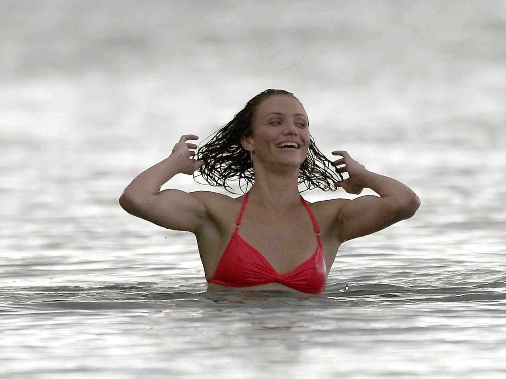 14030, KAUAI, HAWAII - Friday February 23 2007. US actresses Drew Barrymore (black bikini) and Cameron Diaz (red tie-string bikini) take a late afternoon dip in the Pacific Ocean with an unidentified female friend. The women made a lot of noise, laughing and joking with each other as they frolicked in the water. A sudden downpour caused the temperature to drop and the ladies all returned to the beach to cover up and get warm again. Barrymore took this time to catch up on her own paparazzi skills
