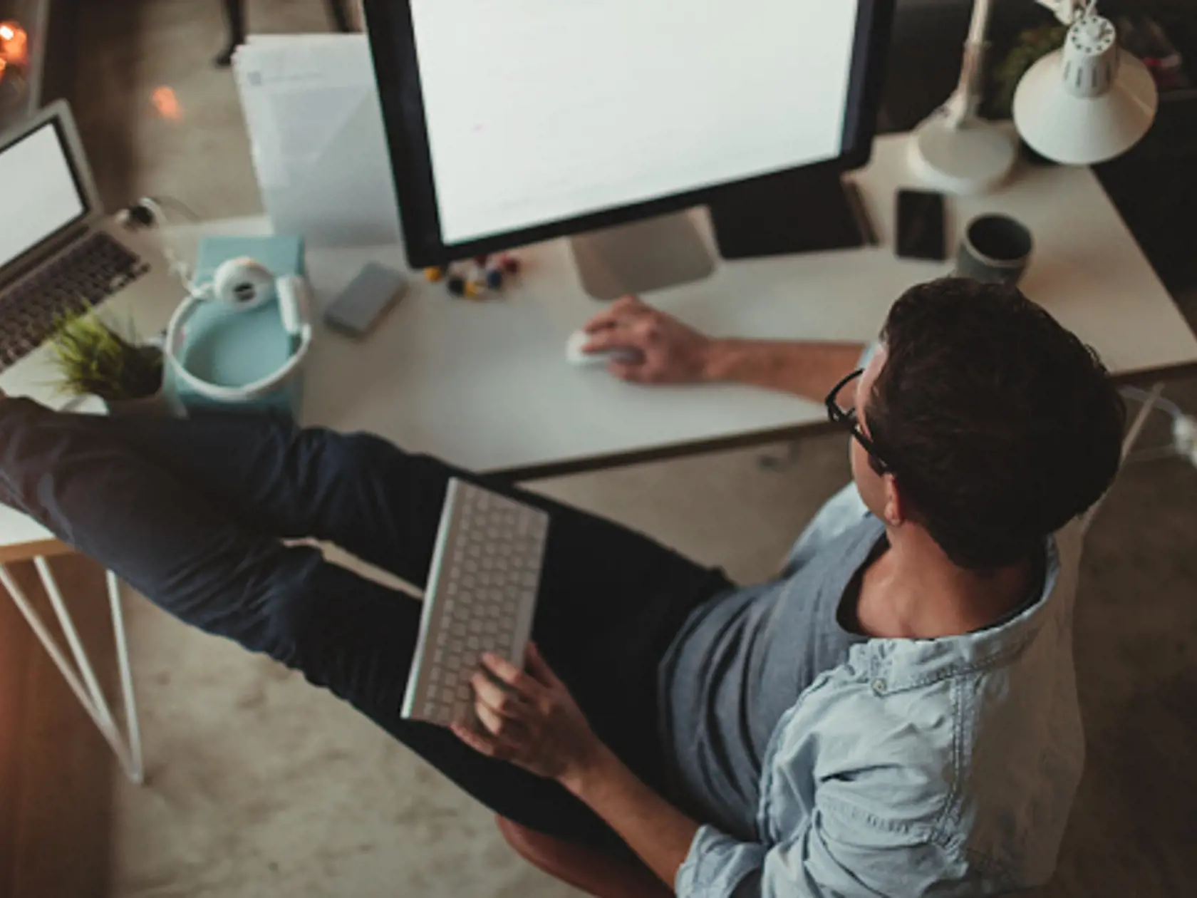 Photo of a young man working on his computer, from his home office