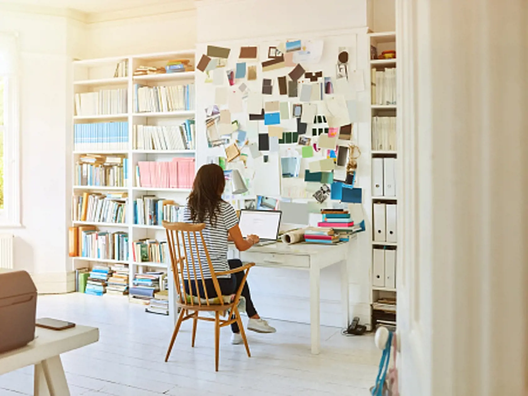 Rear view of pregnant woman sitting in home office and working on laptop