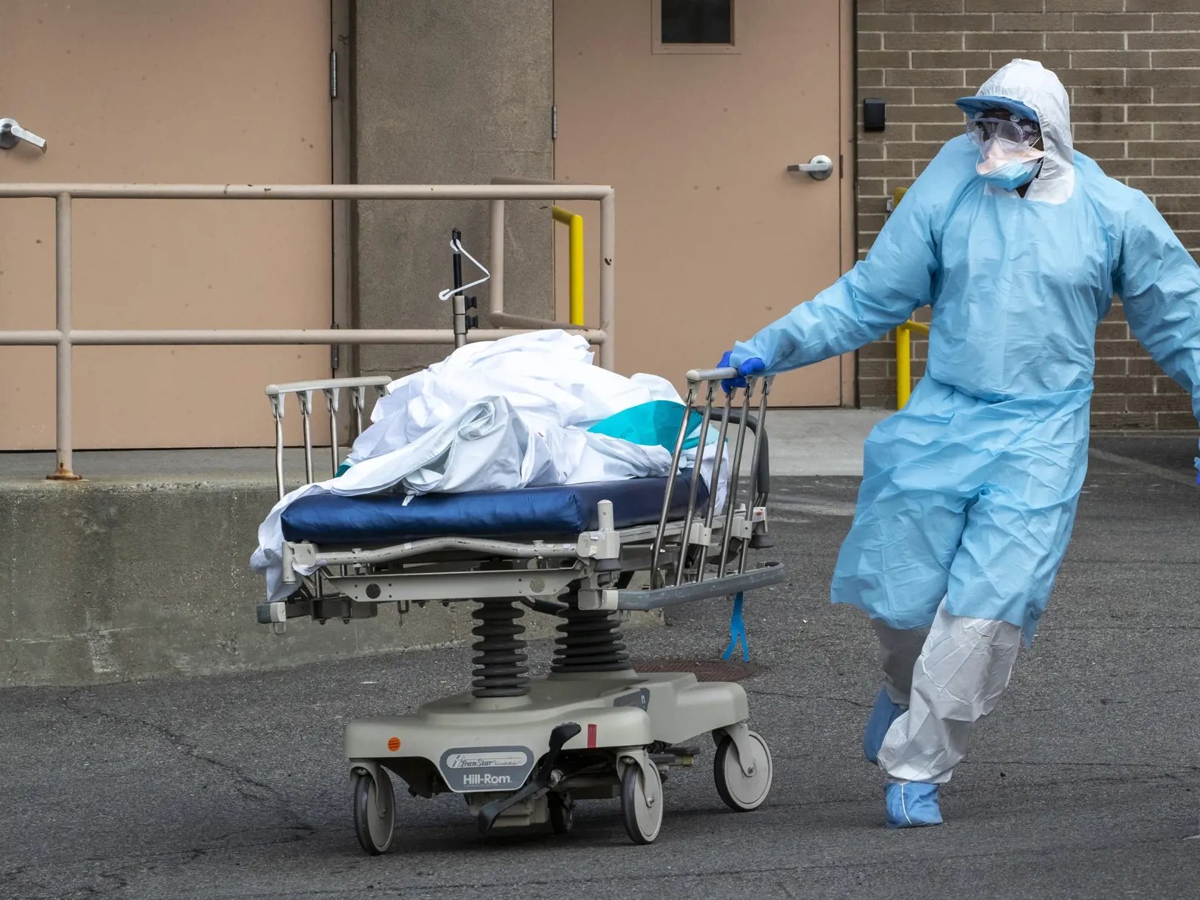 JB 16 New York - Zdravotník v ochrannom odeve prepravuje telo obete pandémie koronavírusu zo zdravotníckeho zariadenia Wycoff Heights Medical Center do chladiarenských kontajnerov pred nemocnicou v New Yorku 2. apríla 2020. Spojené štáty patria medzi krajiny, ktoré epidémia koronavírusu postihla najviac. Novým druhom koronavírusu je tam nakazených najmenej 215.000 ľudí a viac ako 5000 následkom nákazy už podľahlo. FOTO TASR/AP

Medical personnel wearing personal protective equipment to protect f