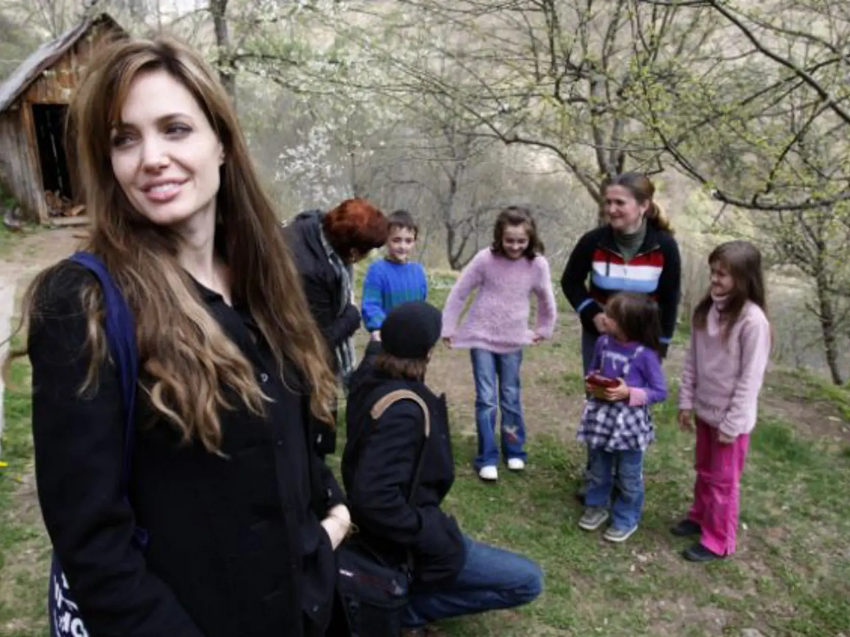 UNHCR goodwill ambassador Angelina Jolie, left, and Brad Pitt, second from left in foreground, visit Bosnian Muslim refugee Sabina Karman, second from left in background, and her four children, in the village of Medjedja, near the eastern Bosnian town of Visegrad, 70 kilometers (43 miles) east of of Sarajevo, Monday, April 5, 2010. Angelina Jolie and Brad Pitt visited Bosnia on Monday, intending to spotlight the plight of 117,000 people who have not been able to return to their homes, even thoug