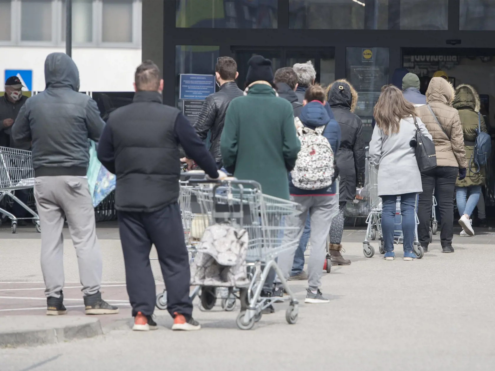 Na snímke čakajúci ľudia stoja v rade pred obchodom. Obchody na Slovensku regulujú vstupy kvôli vírusu Covid-19.