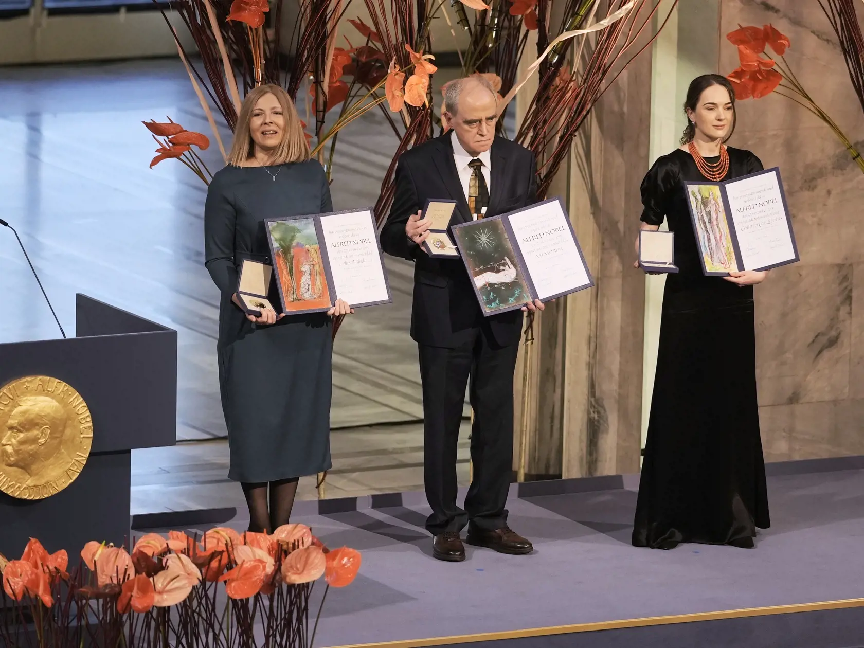 JB 66 Oslo - Zľava Oleksandra Matvijčuková, riaditeľka ukrajinskej ľudskoprávnej organizácie Centrum pre občianske slobody (CCL), Jan Račinskij, predseda ruskej ľudskoprávnej organizácie Memorial a Natallia Pincjuková, manželka väzneného bieloruského aktivistu Alesa Biaľackého pózujú s Nobelovými cenami za mier   počas slávnostného odovzdávania Nobelovej ceny za mier za rok 2022 v radnici v Osle 10. decembra 2022. Tohtoroční laureáti Nobelovej ceny za mier ohlásení v októbri, predstavujú symboli