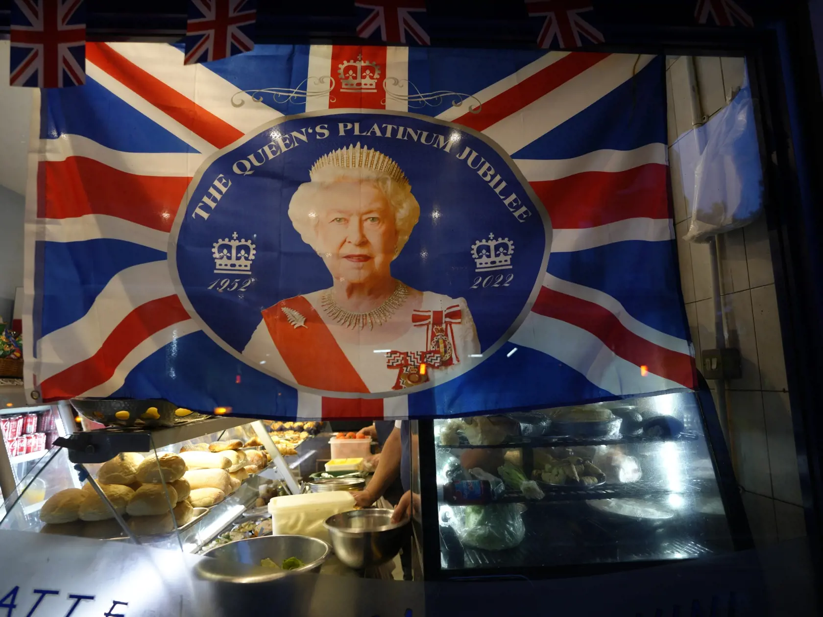 Portrét britskej kráľovnej Alžbety II. na zástave visí v kaviarni neďaleko Buckinghamského paláca v Londýne 9. septembra 2022.