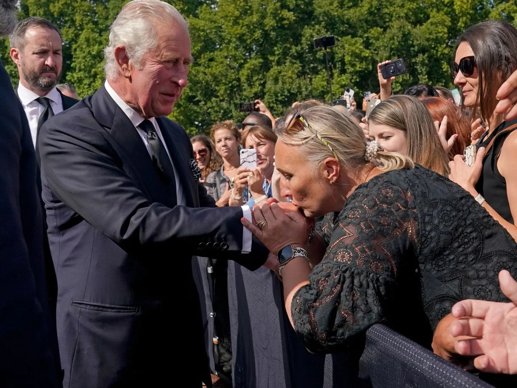 Britka bozkáva ruku kráľovi Karolovi III. pred Buckinghamským palácom v Londýne 9. septembra 2022. Kráľ sa na miesto dostavil, aby si pozrel odkazy a pocty po štvrtkovej smrti kráľovnej Alžbety II., ktoré pred palác priniesli tisíce ľudí.
