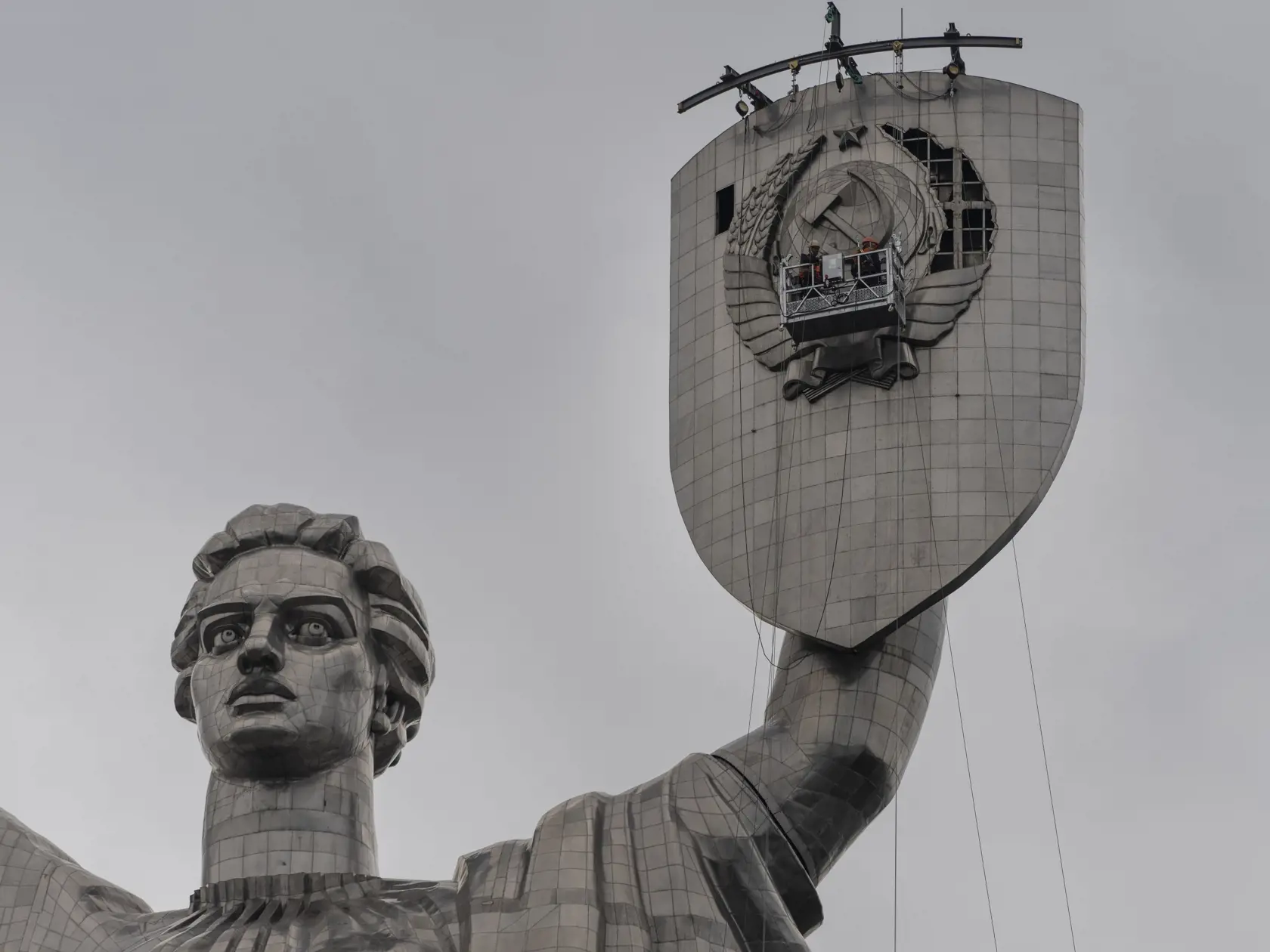 Na snímke zamestnanci pripravujú odstránenie sovietskeho znaku zo štítu pamätníka Matka vlasť v Kyjeve na Ukrajine v pondelok 31. júla 2023.