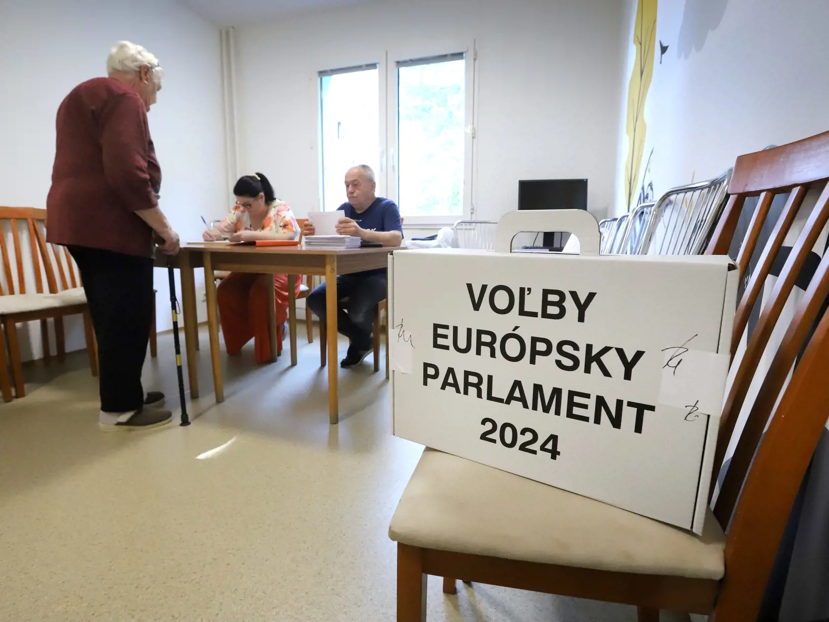 Na snímke dôchodkyňa si preberá hlasovacie lístky od členov volebnej komisie vo volebnej miestnosti v zariadení pre seniorov Jeseň počas volieb do Európskeho parlamentu v Banskej Bystrici v sobotu 8. júna 2024.