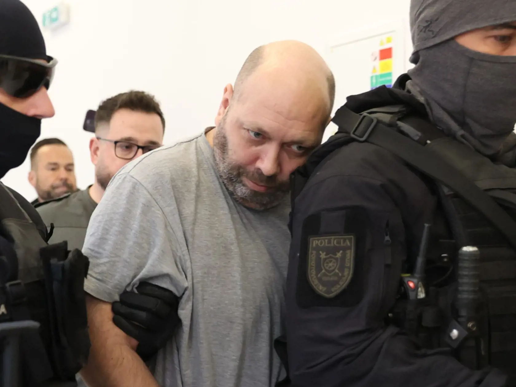Tomáša (44), obvineného z vraždy svojich rodičov, privádzajú kukláči priviedli na súd 18. októbra 2024.