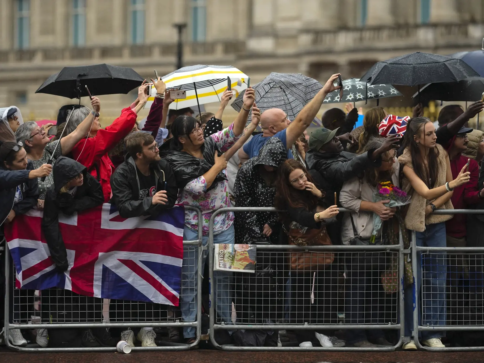 Ľudia čakajú na príchod pohrebného voza vezúceho rakvu s telesnými pozostatkami zosnulej britskej kráľovnej Alžbety II. pred Buckinghamským palácom v Londýne 13. septembra 2022. Rakvu britskej kráľovnej Alžbety II. previezli dnes letecky zo Škótska do Londýna. Následne rakvu majú previezť do Buckinghamského paláca, londýnskeho sídla kráľovskej rodiny, kde sa večer zhromaždil dav ľudí. Kráľovná Alžbeta II. zomrela vo štvrtok 8. seprembra popoludní vo svojom škótskom sídle Balmoral.