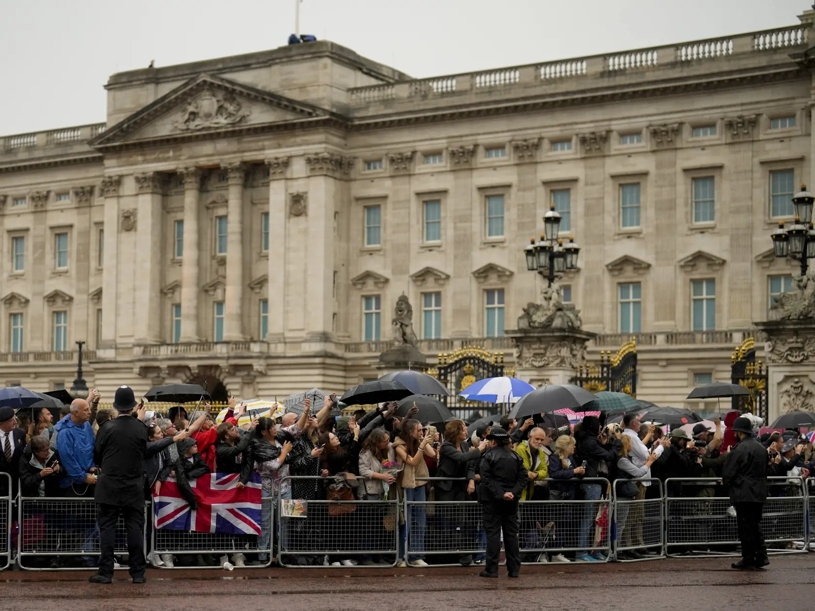 Ľudia čakajú na príchod pohrebného voza vezúceho rakvu s telesnými pozostatkami zosnulej britskej kráľovnej Alžbety II. pred Buckinghamským palácom v Londýne 13. septembra 2022. Rakvu britskej kráľovnej Alžbety II. previezli dnes letecky zo Škótska do Londýna. Následne rakvu majú previezť do Buckinghamského paláca, londýnskeho sídla kráľovskej rodiny, kde sa večer zhromaždil dav ľudí. Kráľovná Alžbeta II. zomrela vo štvrtok 8. seprembra popoludní vo svojom škótskom sídle Balmoral.