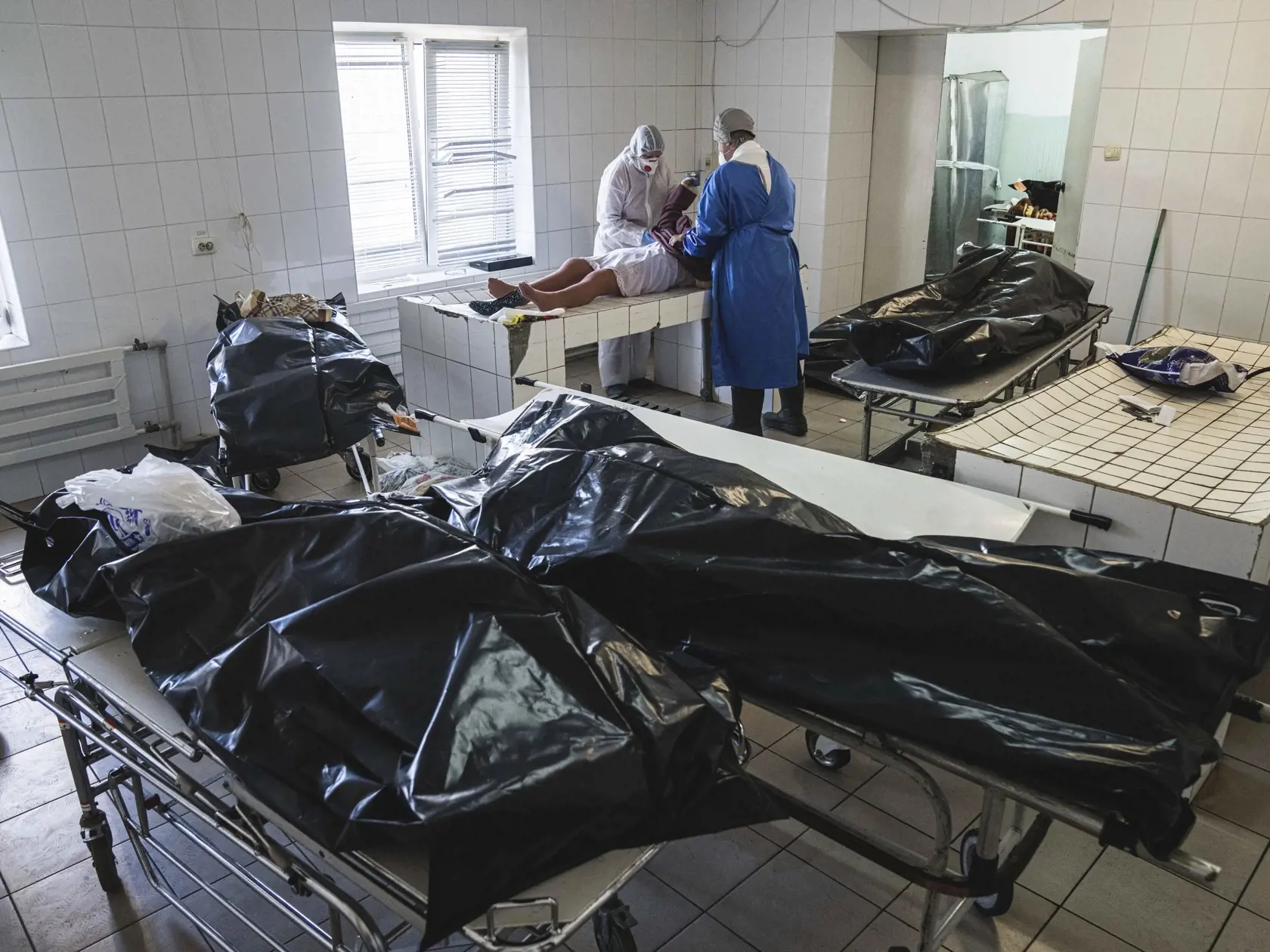 WA 42 Kachovka - Patológovia v špeciálnych ochranných odevoch obliekajú telo obete, ktorá podľahla ochoreniu COVID-19 v márnici nemocnice v meste Kachovka na juhu Ukrajiny v nedeľu 7. novembra 2021. Ukrajina patrí ku krajinám s najnižšou zaočkovanosťou v rámci Európy a nedostatočne financovaným systémom zdravotnej starostlivosti. FOTO TASR/AP