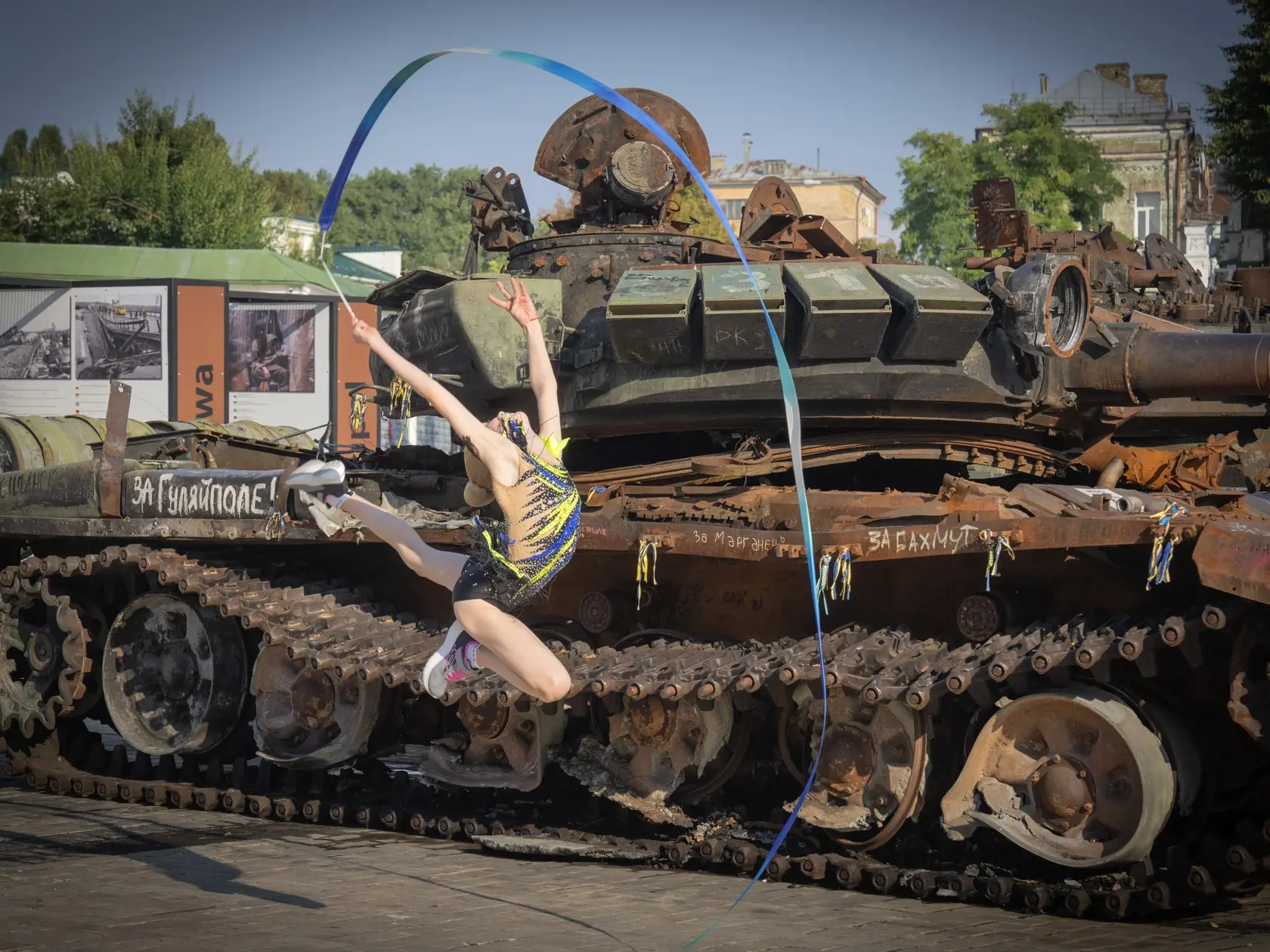 WA 26 Kyjev - Gymnastka vystupuje so stuhou pri zničených ruských tankov, ktoré vystavili v centre Kyjeva v pondelok 20. augusta 2023. Ukrajina v pondelok zoradila trosky ruských tankov a bojových vozidiel pozdĺž centrálneho ťahu hlavného mesta Kyjev. Ide o súčasť príprav na oslavy Dňa nezávislosti Ukrajiny, ktorý sa už po druhý raz bude konať vo vojnových podmienkach.  Štátnym sviatkom si Ukrajina vo štvrtok pripomenie 32 rokov postsovietskej nezávislosti od Moskvy, čo bude presne 18 mesiacov p