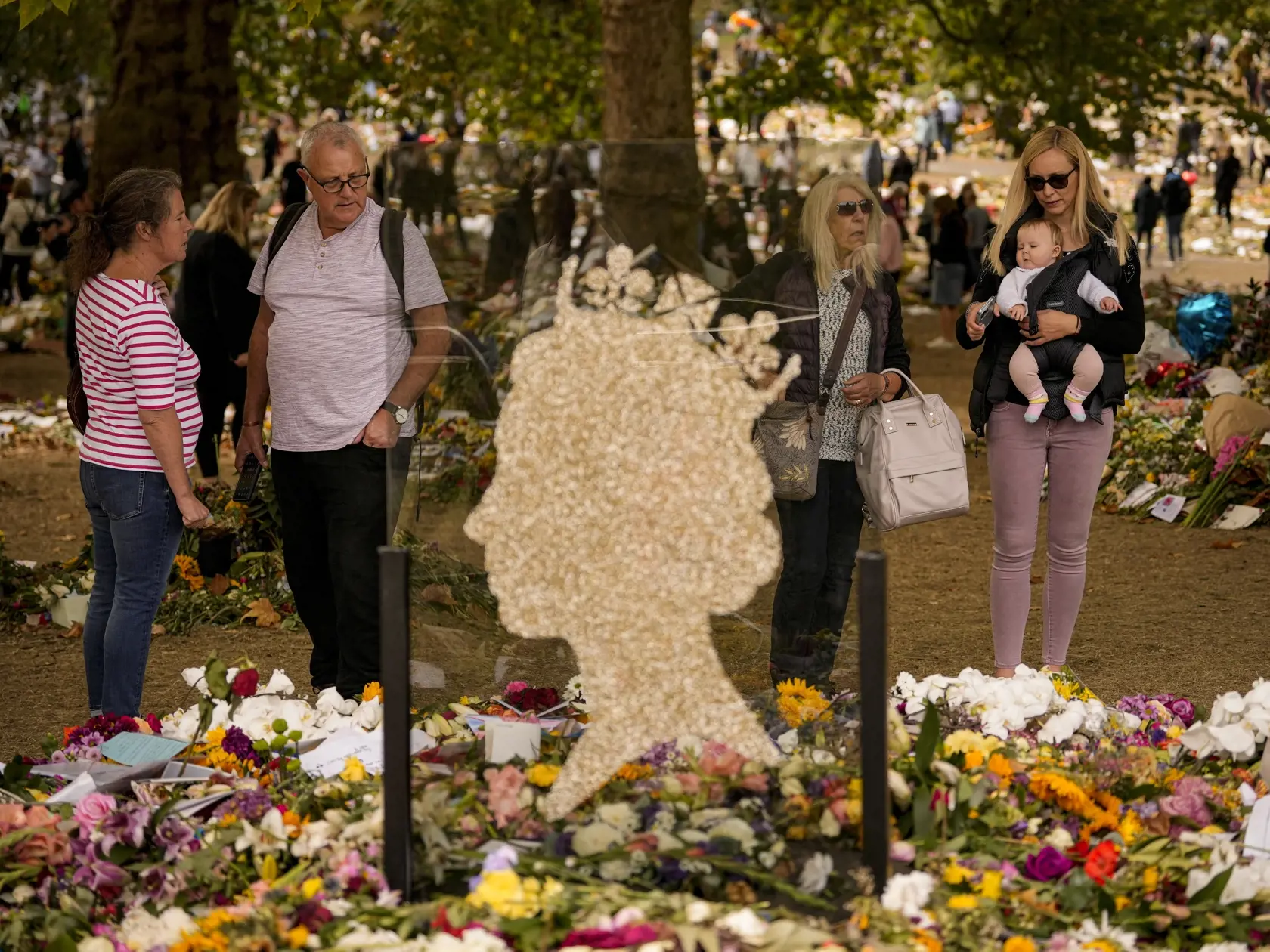WA 23 Londýn - Ľudia prinášajú kvety na pamiatku zosnulej britskej kráľovnej Alžbety II. do Green Parku, jedného z ôsmich kráľovských parkov v Londýne, deň po panovníčkinom pohrebe v utorok 20. septembra 2022. Panovníčku, ktorá zomrela vo veku 96 rokov 8. septembra, pochovali na Windsorskom hrade po boku jej zosnulého manžela princa Philipa v pondelok večer 19. septembra. Na miesto posledného odpočinku ju uložili po súkromnom obrade za účasti blízkej rodiny. FOTO TASR/AP    

People bring floral