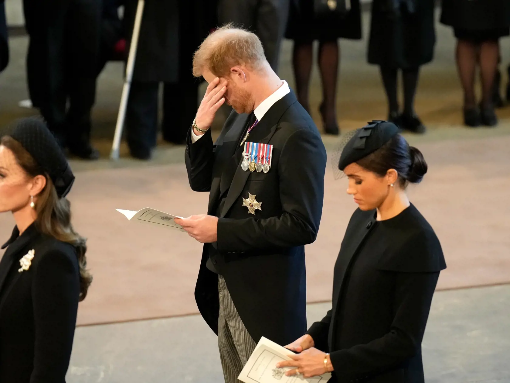 Princ Harry, ktorému nedovolili, aby si na smútočný pochod obliekol vojenskú uniformu, bol očividne zo smrti svojej babky zdrvený. Emocionálnu podporu mu poskytovala manželka Meghan, ktorá ho dokonca v istom momente, napriek kráľovskému protokolu, chytila za ruku. Obaja sa potom pri odchode zo sály s kráľovniným telom držali.