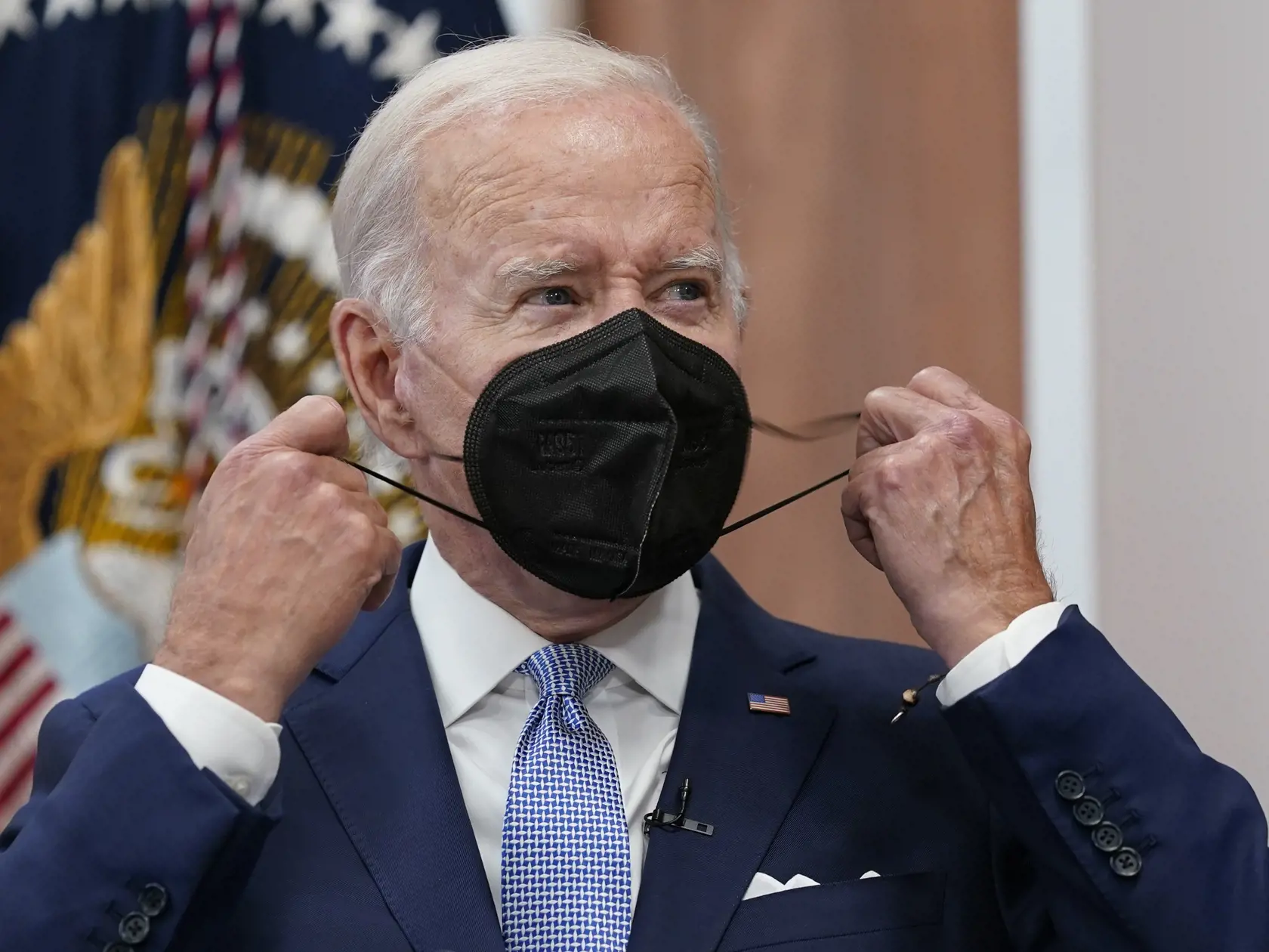 Na archívnej snímke z 28. júla 2022 americký prezident Joe Biden si dáva dole z tváre respirátor v Bielom dome vo Washingtone.