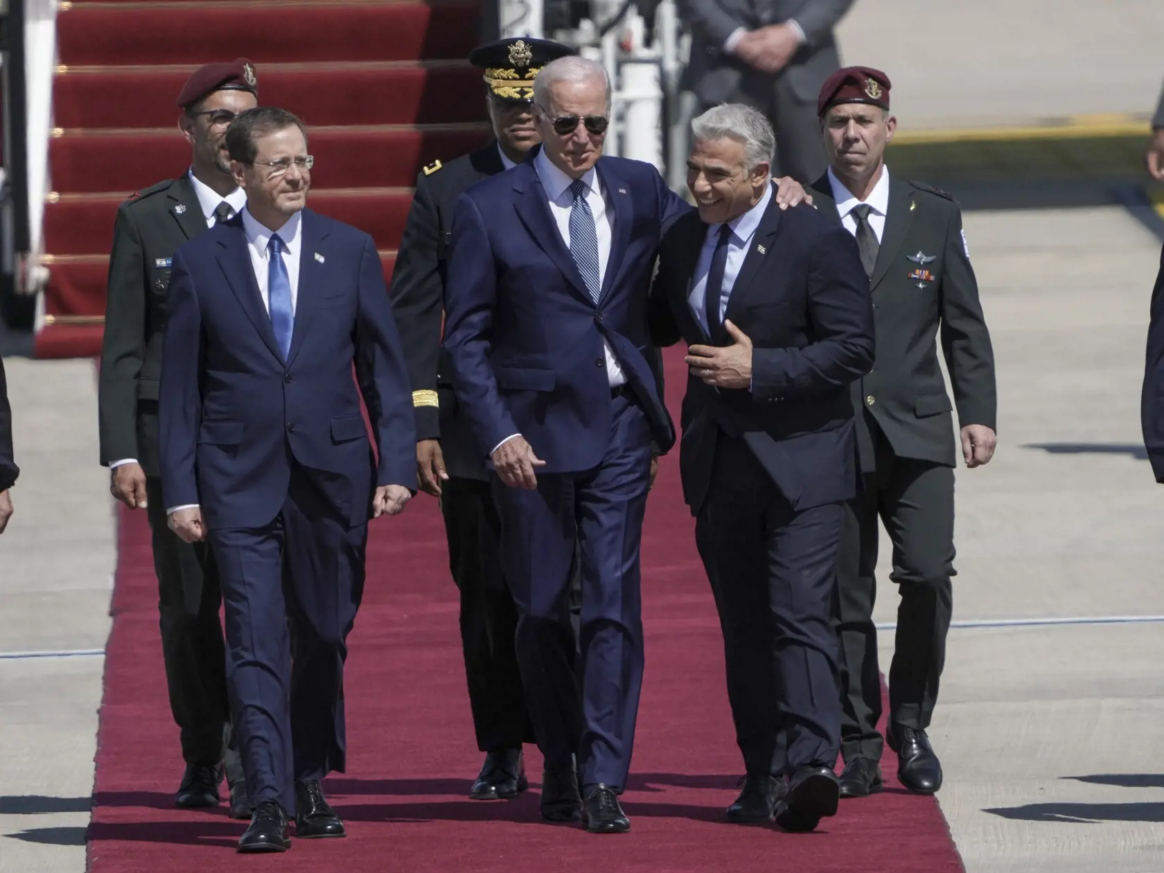 Izraelský premiér Yair Lapid (vpravo) a izraelský prezident Isaac Herzog (vľavo) vítajú amerického prezidenta Joea Bidena (uprostred) po jeho prílete do Izraela na letisku Bena Guriona v Tel Avive 13. júla 2022.