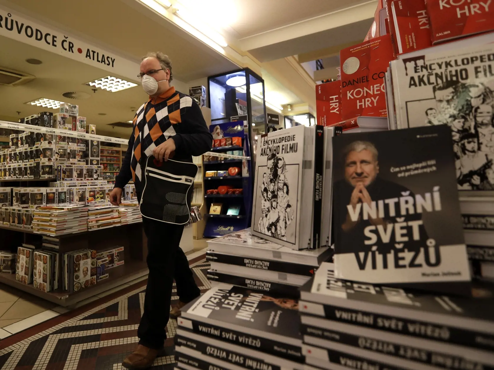 WA 35 Praha - Návštevník s ochranným rúškom kráča v kníhkupectve, ktoré opätovne otvorili po uvoľnení pravidiel počas koronakrízy v pondelok 27. apríla 2020. Vláda kvôli priaznivému vývoju epidémie nového typu koronavírusu v krajine od pondelka povolila otvorenie obchodov a ďalších prevádzok mimo obchodných centier s plochou do 2500 metrov štvorcových so samostatným vchodom. Zrušila tiež zákaz voľného pohybu osôb - vrátane cestovania do zahraničia. FOTO TASR/A