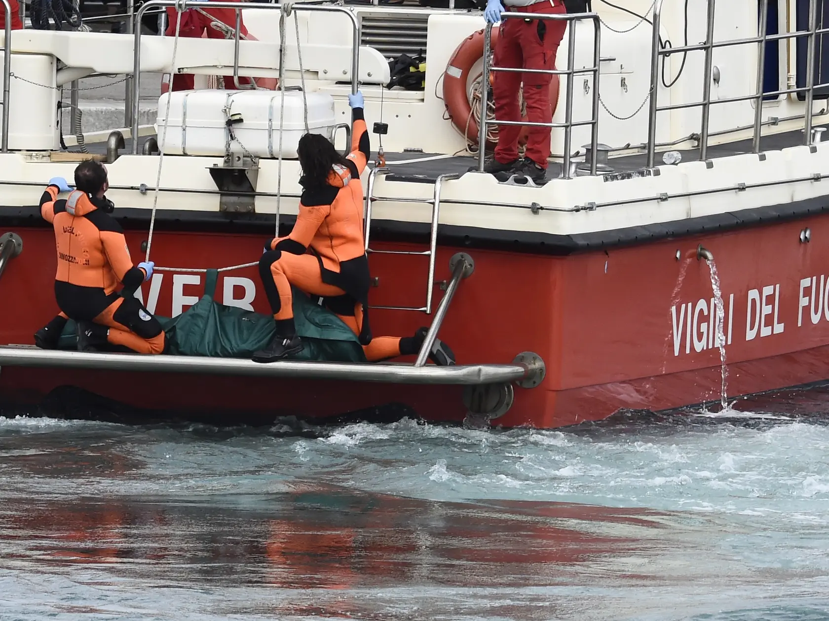 Talianski potápači vynášajú telo jednej z obetí potopenej plachetnice Bayesan v prístave v meste Porticello neďaleko Palerma na talianskom ostrove Sicília.