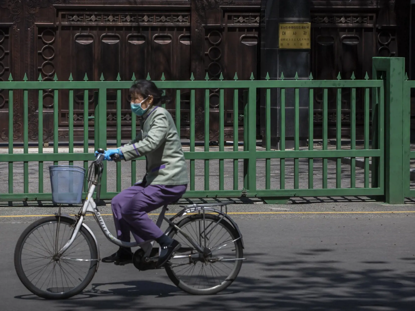 WA 9 Peking - Žena na bicykli s ochranným rúškom na tvári, ktoré má v rámci prevencie proti šíreniu nového koronavírusu, prechádza okolo severokórejského veľvyslanectva v Pekingu v utorok 21. apríla 2020.