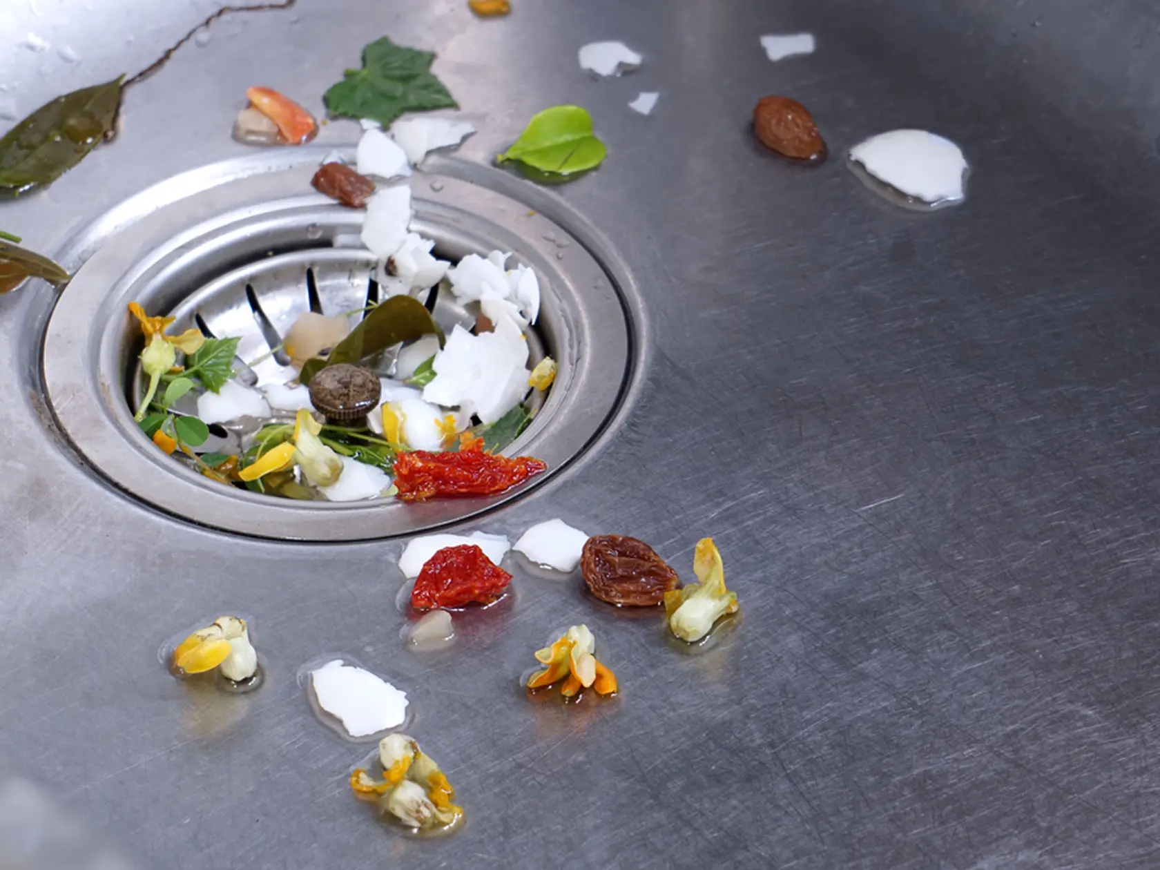 Food waste from the washing up in the sink and trash traps grid of drainage holes. The garbage is filtered with a sieve and placed in the trash for disposal.