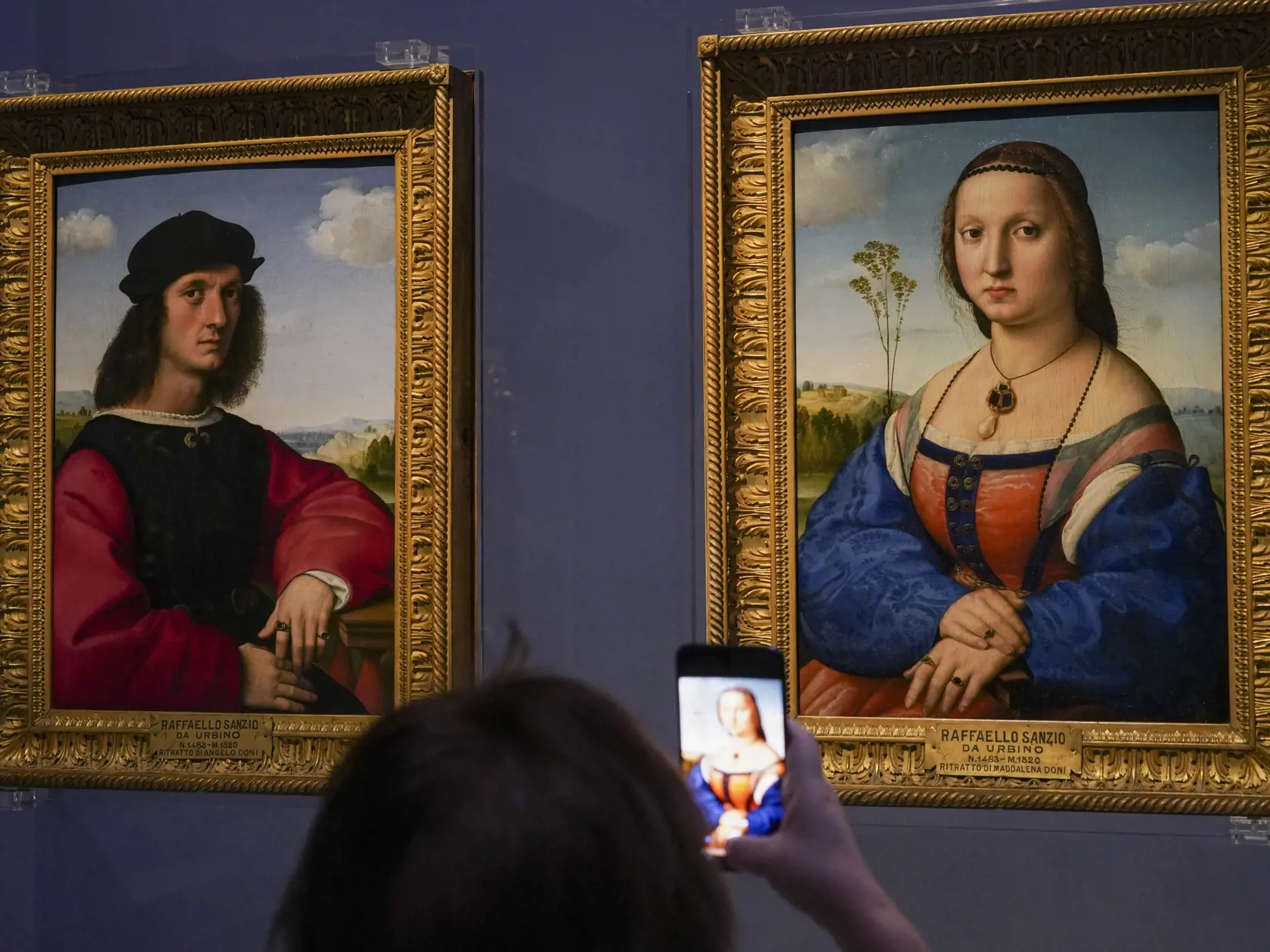 Na snímke novinár si fotografuje portrét Angela a portrét Maddalena Doni (vpravo) od talianskeho renesančného maliara Raffaella Sanzia da Urbinoho v galérii Uffizi počas novinárskej prehliadky v deň jej znovuotvorenia pre verejnosť 3. júna 2020 vo Florencii.