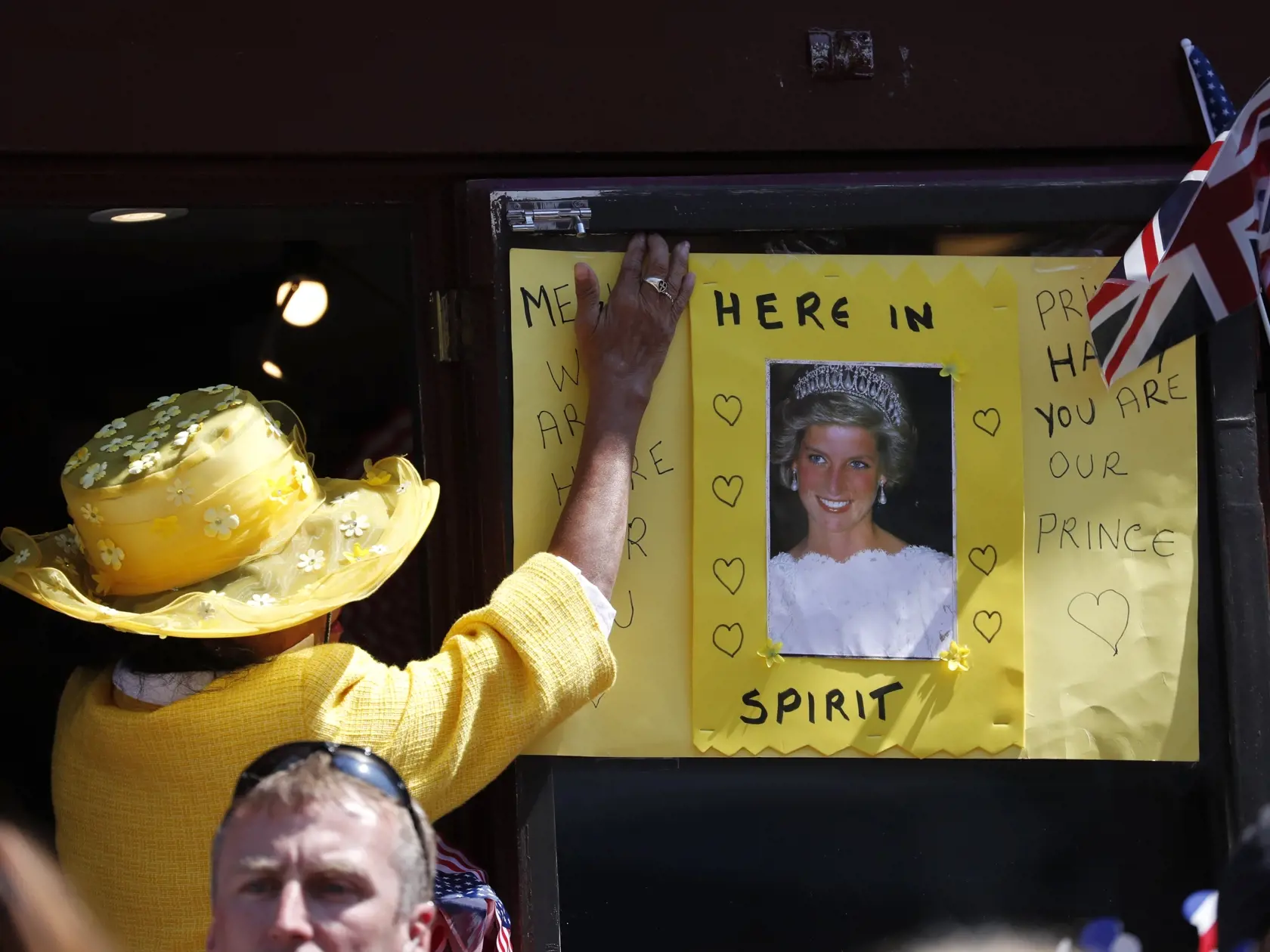 A woman attaches a poster with a photo of Princess Diana outside the wedding ceremony of Prince Harry and Meghan Markle at St. George's Chapel in Windsor Castle in Windsor, near London, England, Saturday, May 19, 2018. (AP Photo/Frank Augstein, pool)