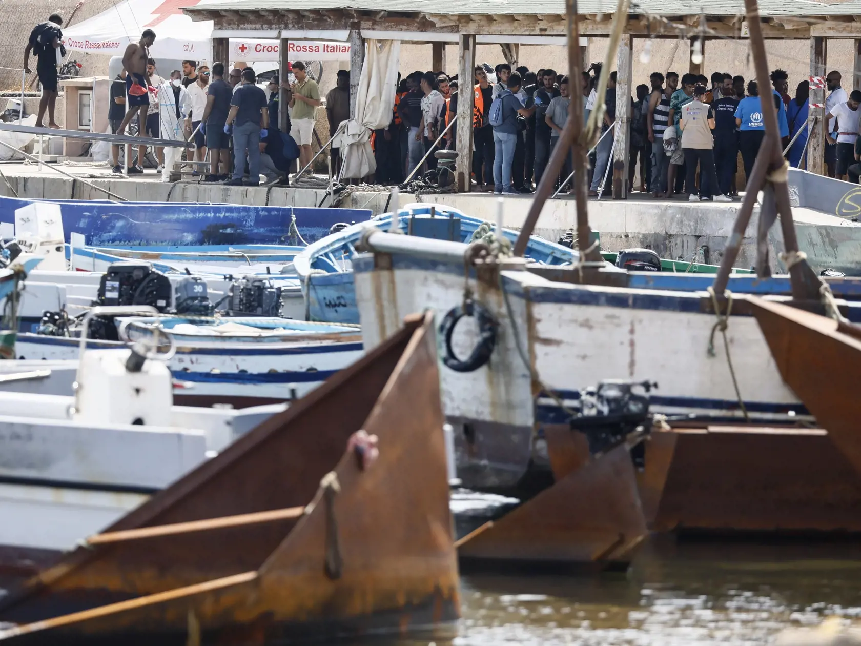 JB 27 Lampedusa - Migranti, ktorých zachránilo  plavidlo talianskej pobrežnej stráže stoja v doku  prístavu talianskeho ostrova Lampedusa 18. septembra 2023 deň po tom, ako tento ostrov navštívila predsedníčka Európskej komisie Ursula von der Leyenová. V Stredozemnom mori je potrebné posilniť letecké aj námorné hliadkovanie v záujme boja proti nelegálnej migrácii. Počas nedeľňajšej návštevy juhotalianskeho ostrova Lampedusa, ktorý v súčasnosti zažíva silný nápor migrantov, to uviedla predsedníčk