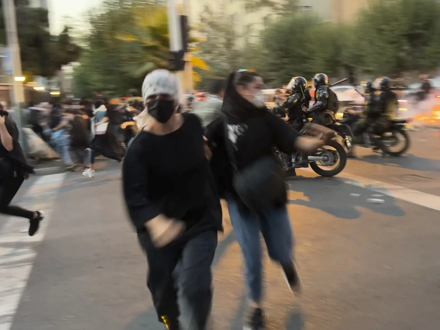 Na snímke z pondelka 19. septembra 2022 od osoby, ktorá nie je zamestnaná v agentúre Associated Press (AP), a ktorú získala agentúra AP mimo Iránu, ženy utekajú pred policajtmi počas protestu proti smrti mladej iránskej ženy Mahsá Amíníovej v centre Teheránu.