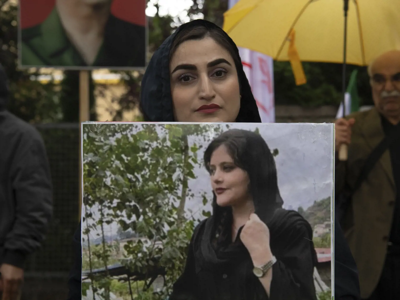 Ľudia držía fotografiu zosnulej mladej Iránky Mahsá Amíníovej počas protestu pred iránskym veľvyslanectvom v Berlíne v utorok 20. septembra 2022. Mravnostná polícia v Teheráne zatkla 22-ročnú Amíníovú za údajné porušenie pravidiel obliekania. Iránka po troch dňoch vo väzbe upadla do kómy a zomrela.