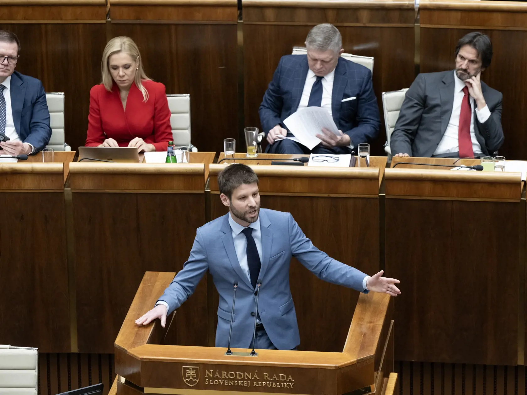 Na snímke uprostred poslanec NR SR Michal Šimečka (Progresívne Slovensko) hovorí počas mimoriadnej schôdze k opozičnému návrhu na vyslovenie nedôvery vláde SR  21. januára 2025 v Bratislave. V pozadí zľava podpredseda vlády SR pre Plán obnovy a odolnosti a využívanie eurofondov Peter Kmec (Hlas-SD), podpredsedníčka vlády a ministerka hospodárstva SR Denisa Saková (Hlas-SD), premiér Robert Fico, vicepremiér a minister obrany SR Robert Kaliňák (obaja Smer-SD). FOTO TASR - Pavel Neubauer