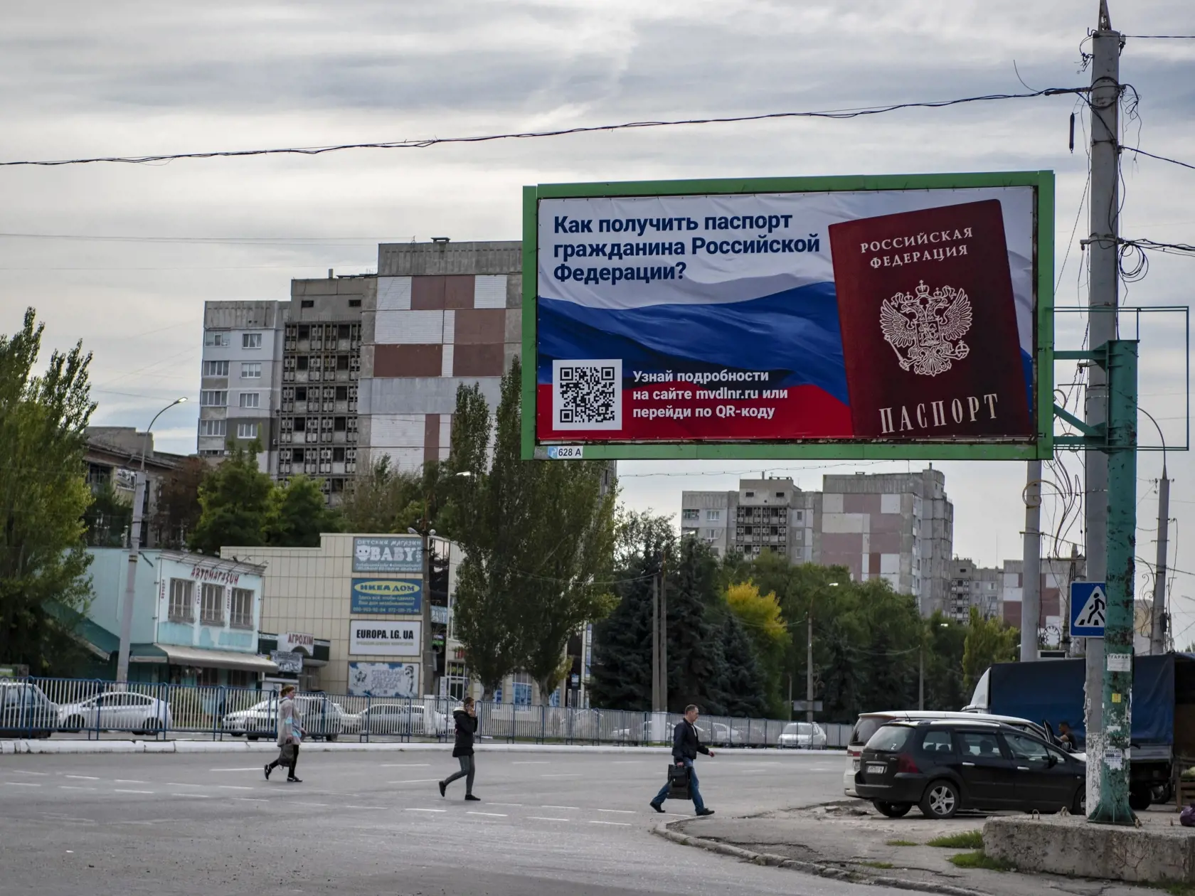WA 12 Luhansk - Ľudia kráčajú cez cestu okolo bilbordu s nápisom "Ako získať ruský pas? pred referendami o pripojení štyroch ukrajinských regiónov k Rusku v Luhansku na východe Ukrajiny vo štvrtok 22. septembra 2022. V štyroch regiónoch, ktoré na Ukrajine okupujú ruské sily, sa v piatok 23. septembra o 7.00 h SELČ začali referendá o ich pripojení k Rusku, informuje agentúra AFP. Prebiehať budú päť dní až do utorka 27. septembra. Konajú sa v samozvaných republikách na východe Ukrajiny – Doneckej 