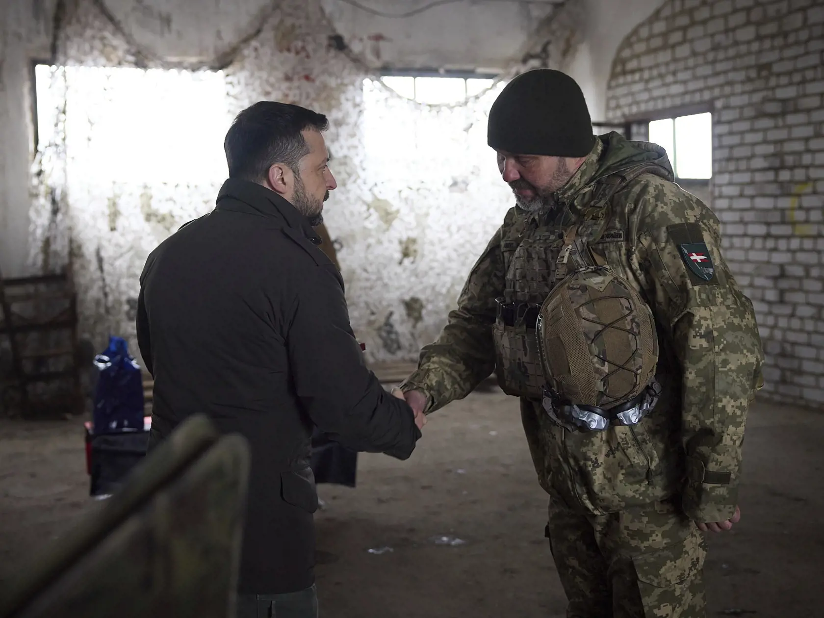 Ukrajinský prezident Volodymyr Zelenskyj (vľavo) si podáva ruku s vojakom počas návštevy frontovej línie v ukrajinskom meste Kupiansk 19. februára 2024.