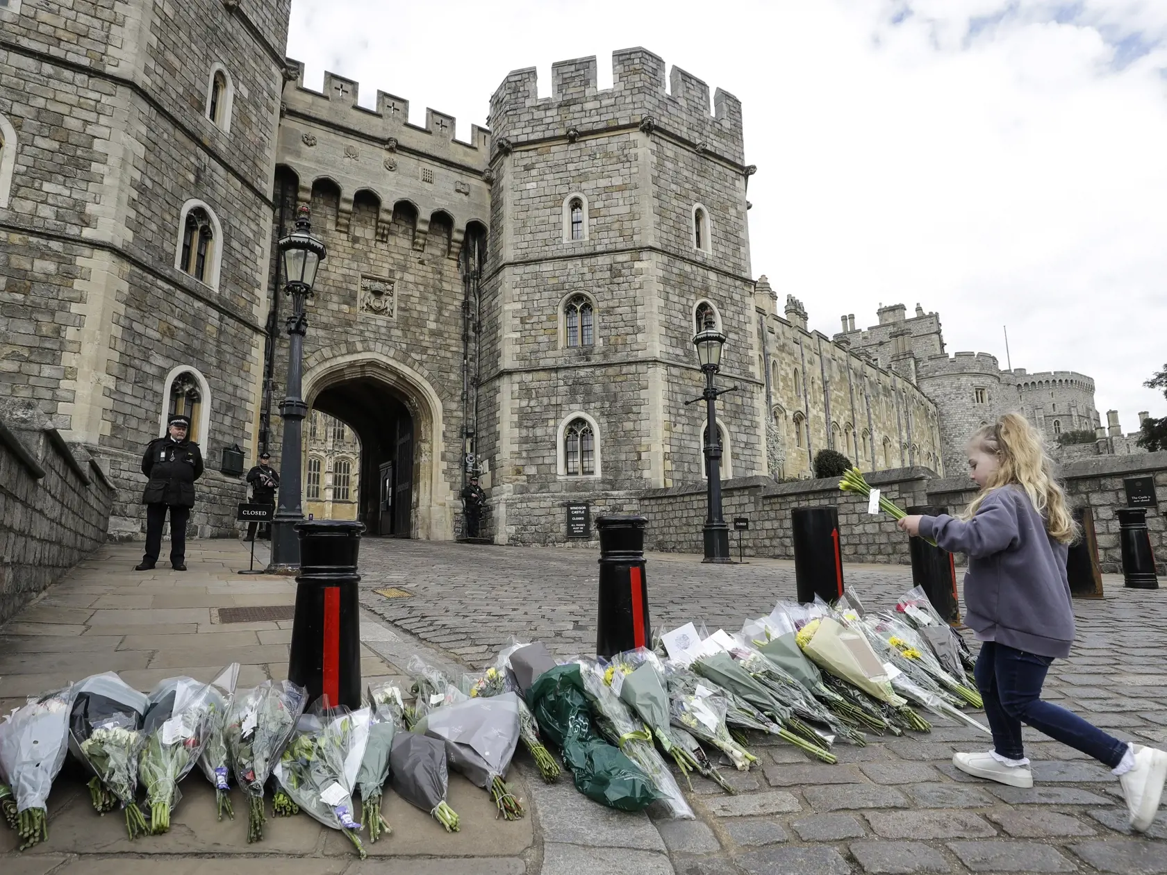 KK18 Windsor - Dievčatko kladie kvety pred Windsorským hradom 9. apríla 2021. Britský princ Philip, manžel kráľovnej Alžbety II., zomrel v piatok vo veku 99 rokov. Oznámil to Buckinghamský palác.  "Jeho kráľovská výsosť zomrela dnes ráno pokojne na Windsorskom zámku," dodal palác s tým, že ďalšie informácie zverejnia v náležitom čase. FOTO TASR/AP
A child lays flowers outside Windsor Castle in Windsor, England after the announcement regarding the death of Britain's Prince Philip, Friday, April 9
